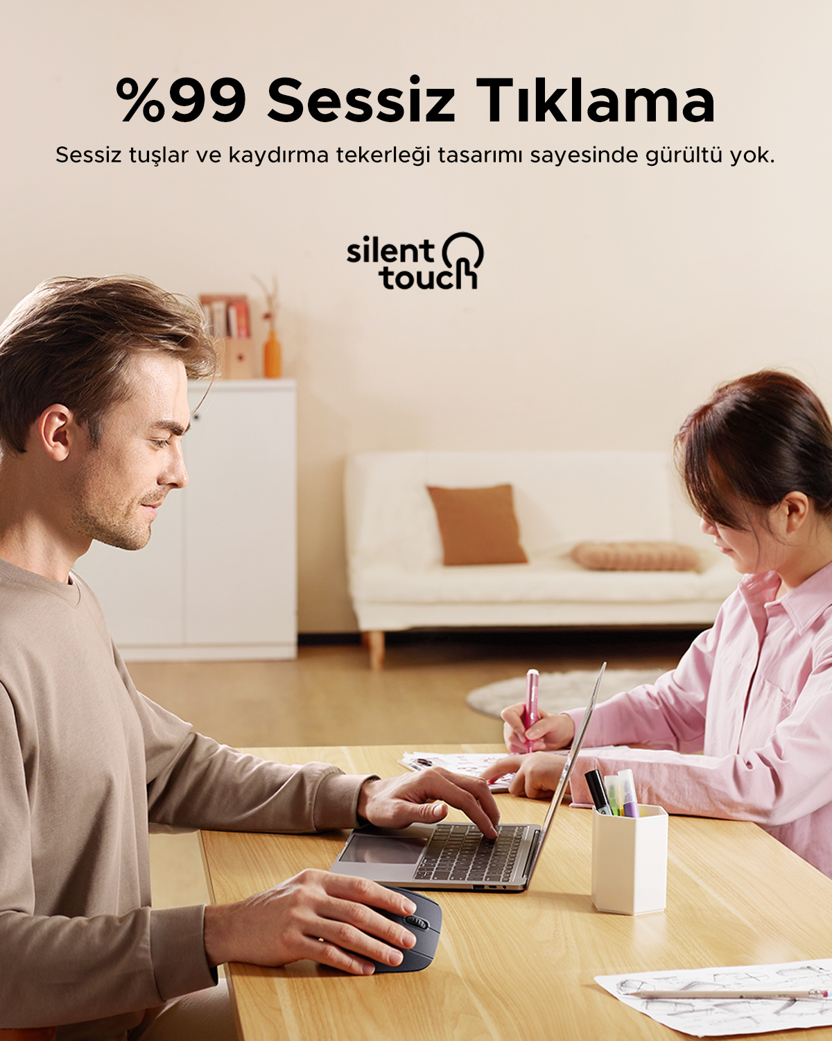 Mężczyzna i kobieta pracują przy laptopie. Mysz i długopisy na stole.