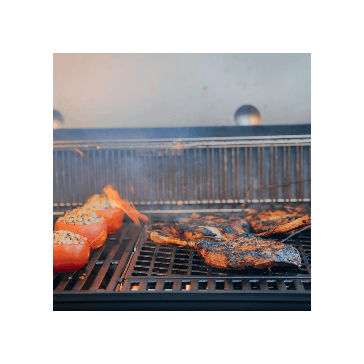 Carne y tomates rellenos en una parrilla con llamas.