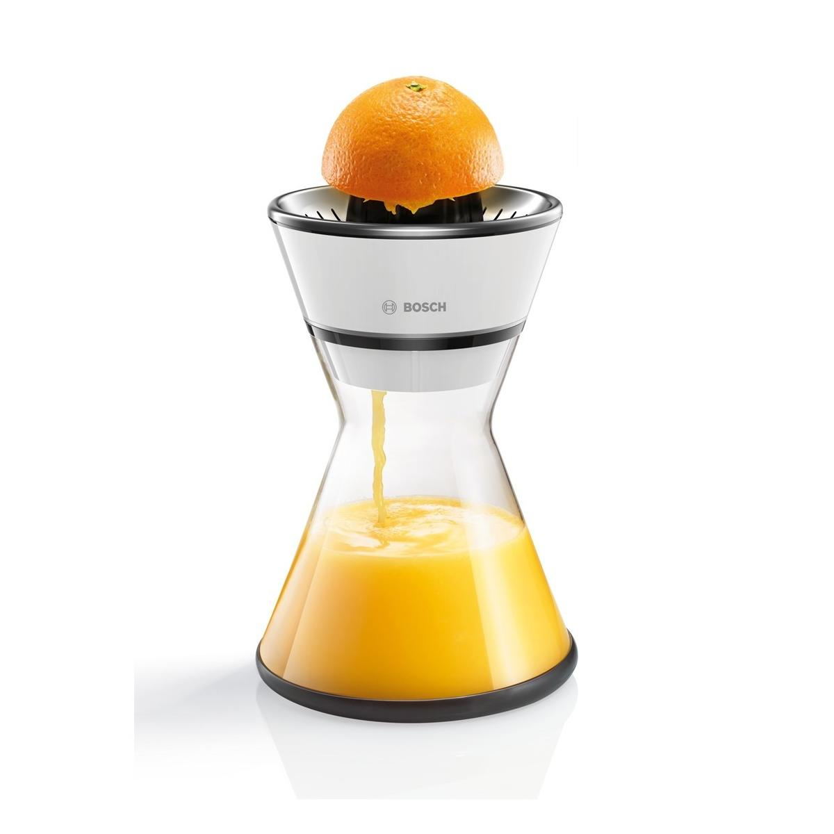 Una naranja se exprime en un exprimidor Bosch, el jugo cae en una jarra de vidrio.