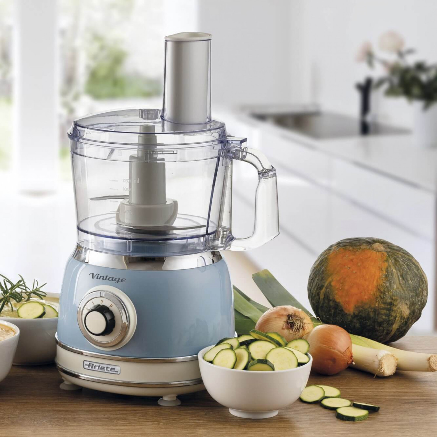 Un robot da cucina vintage azzurro con verdure come zucchine, cipolle e porri.