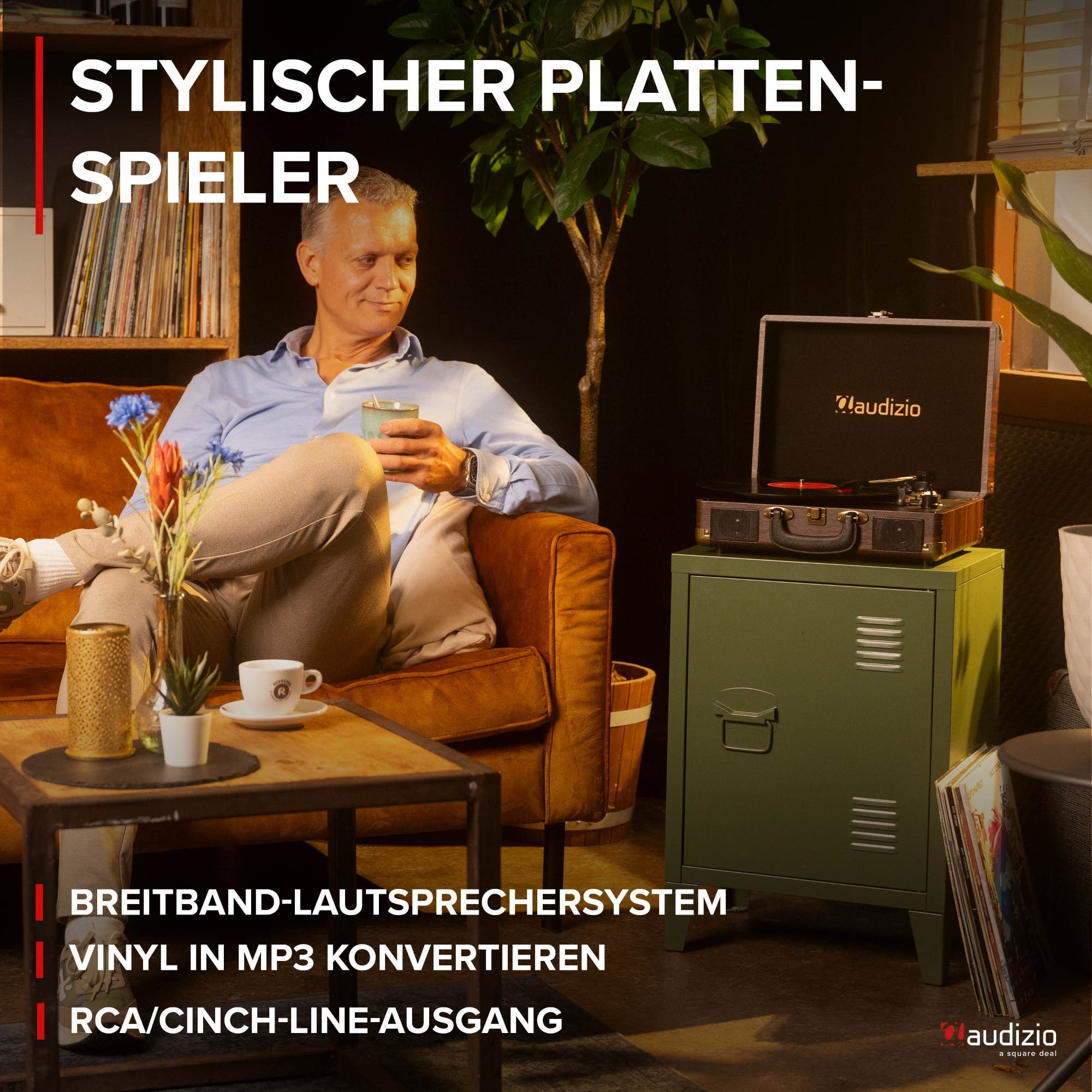 Mann sitzt auf Sofa, hält Tasse. Plattenspieler auf Schrank.