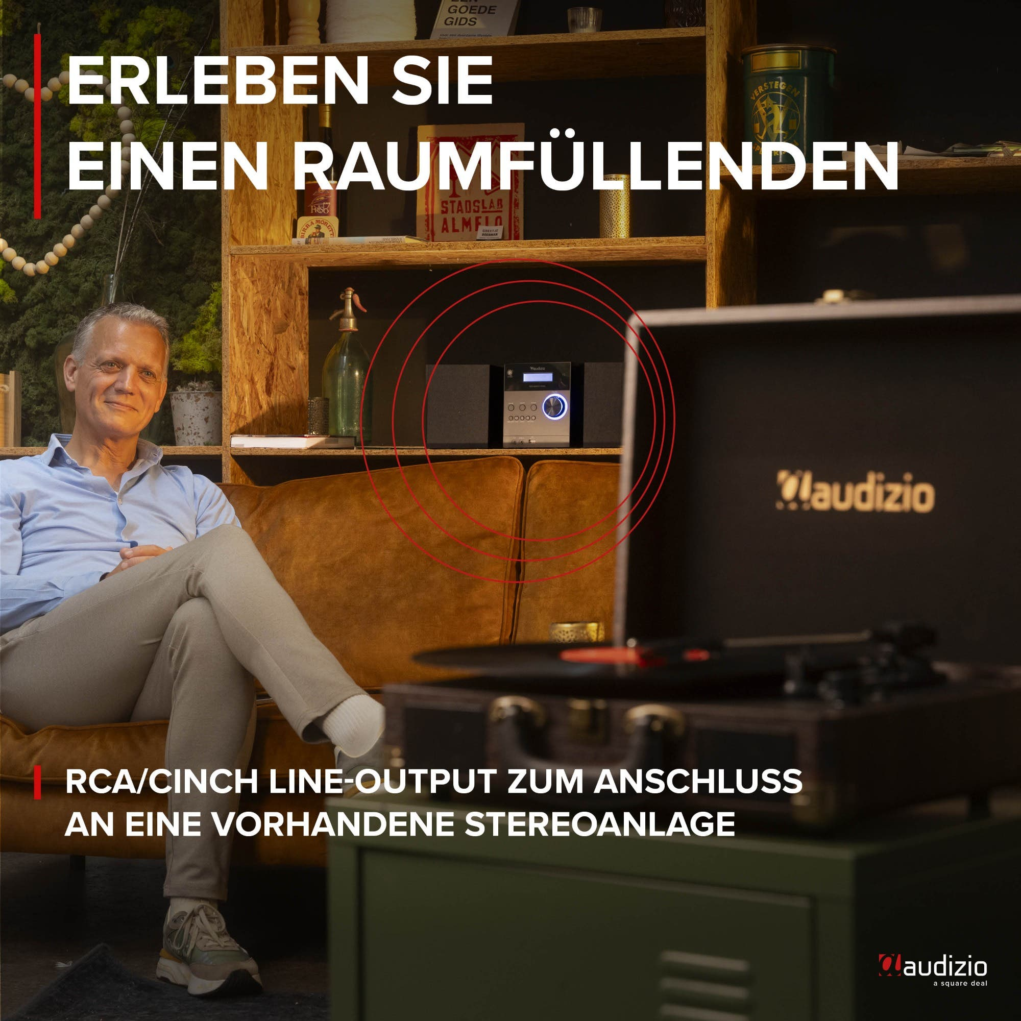 Mann sitzt auf Sofa, daneben Plattenspieler und Stereoanlage.