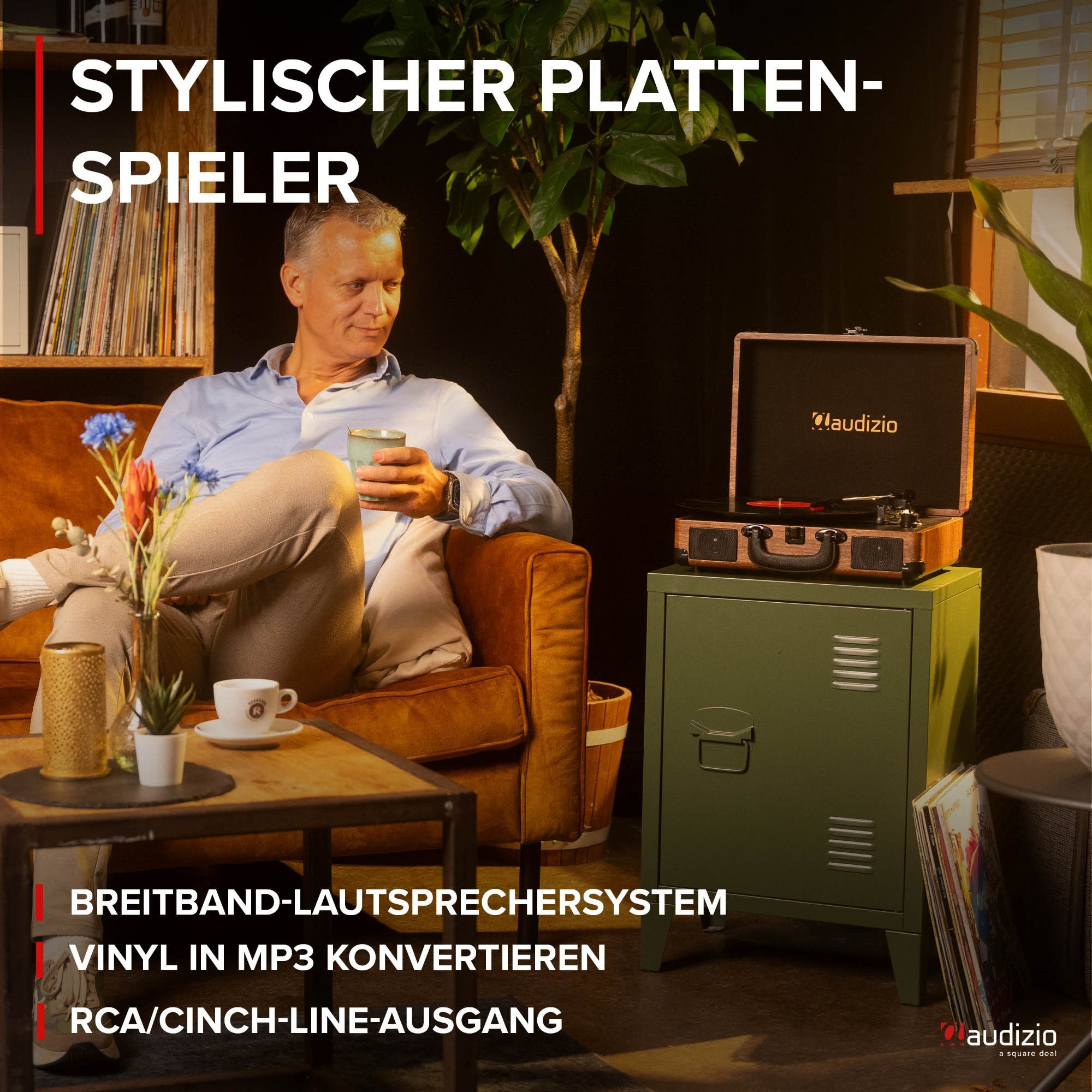Mann sitzt auf Sofa, daneben Plattenspieler auf Schrank. Dekoration im Raum.