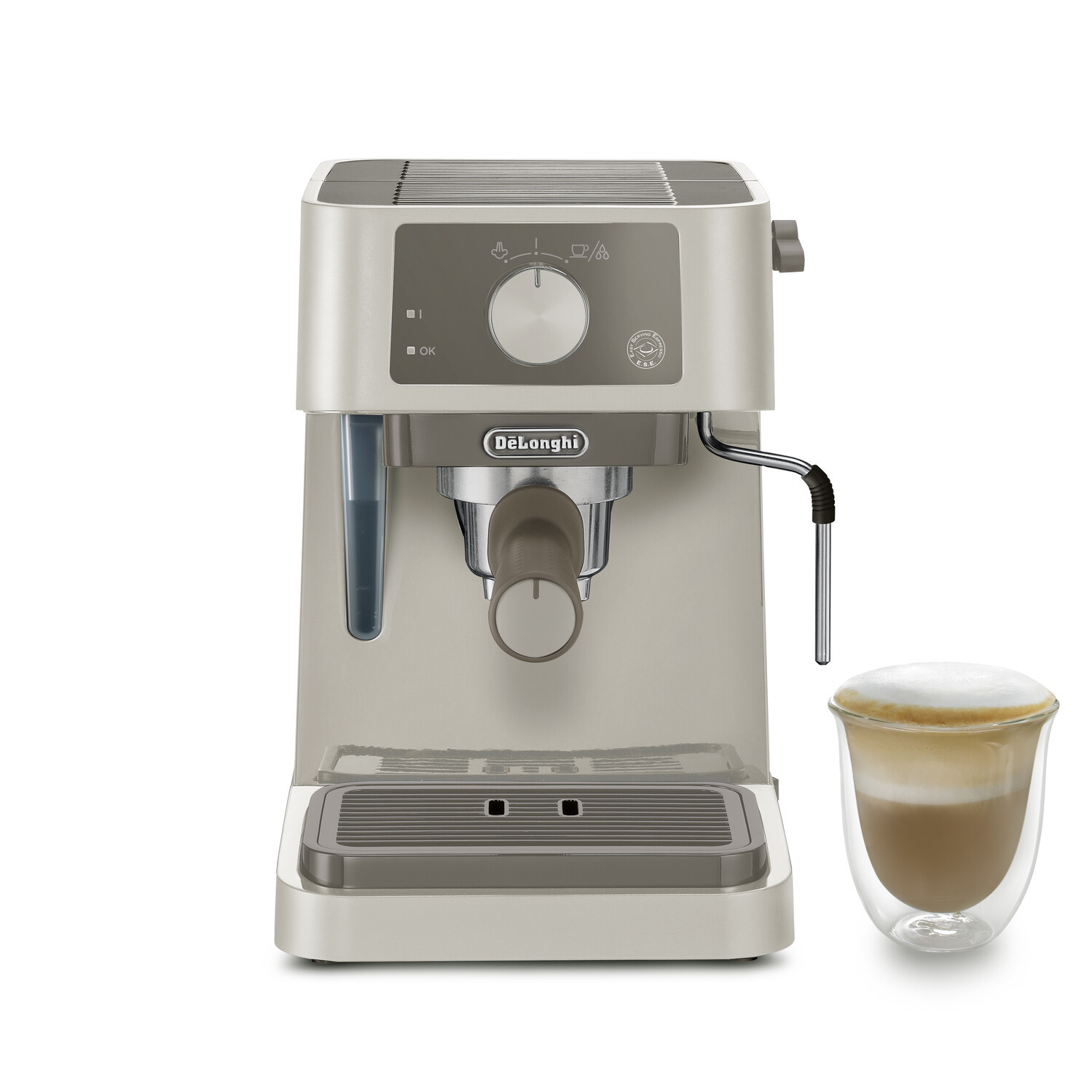 Eine beige DeLonghi Espressomaschine mit einem Glas Cappuccino daneben.