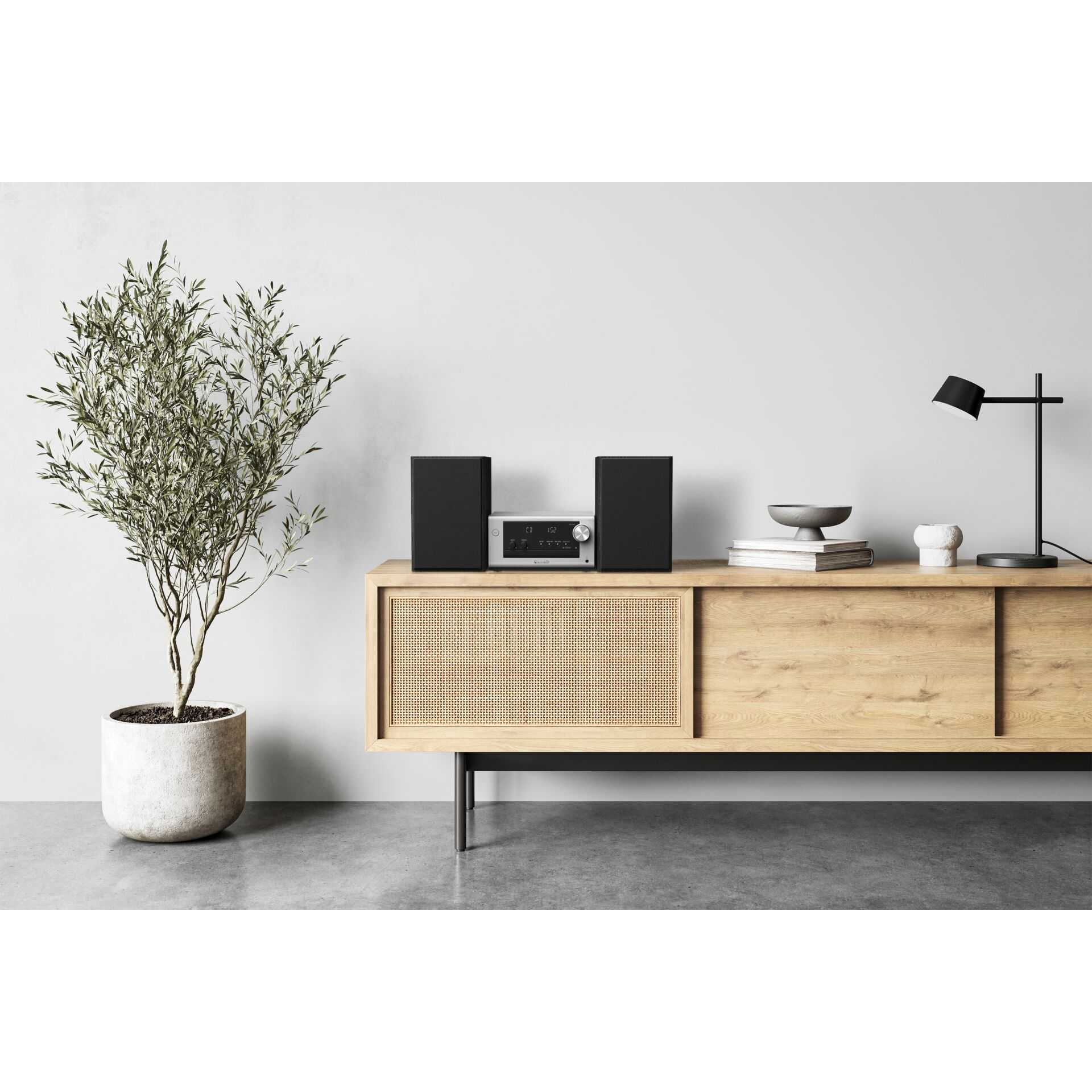Ein silbernes Stereo-System mit schwarzen Lautsprechern auf einem Holzschrank.