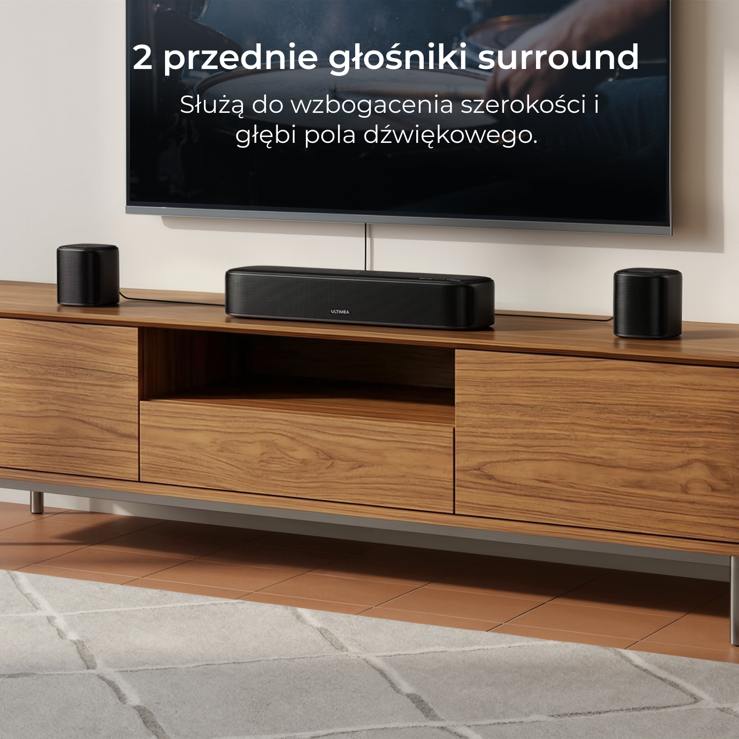 Czarny soundbar i dwa głośniki satelitarne na drewnianej szafce przed telewizorem.
