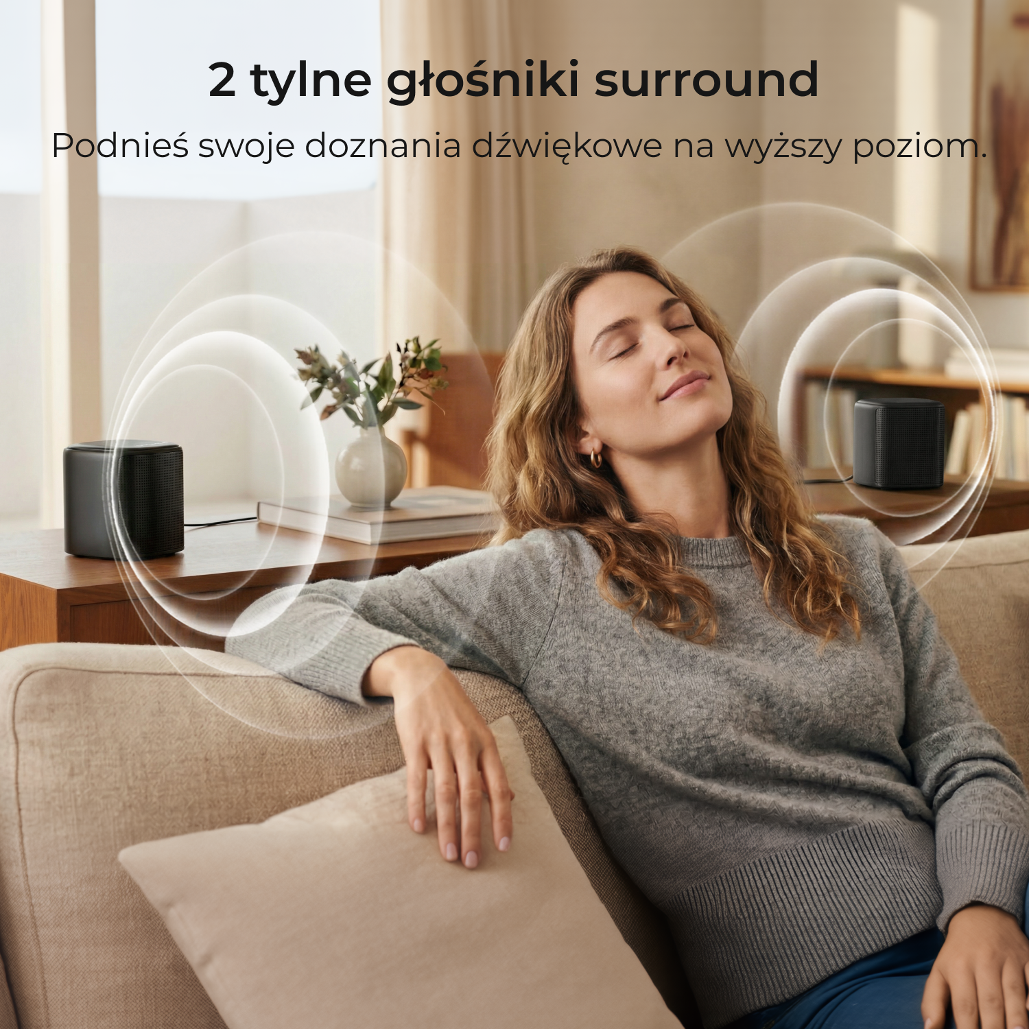 Kobieta relaksuje się na kanapie, dwa czarne głośniki tworzą dźwięk przestrzenny.