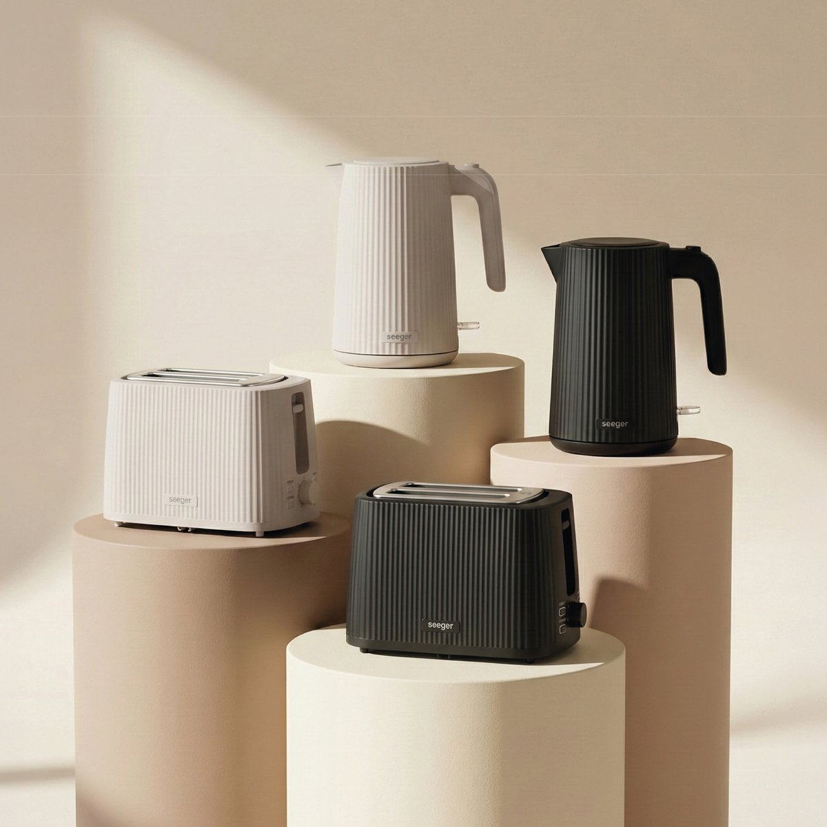 Two white and two black toasters and kettles, arranged on pedestals.