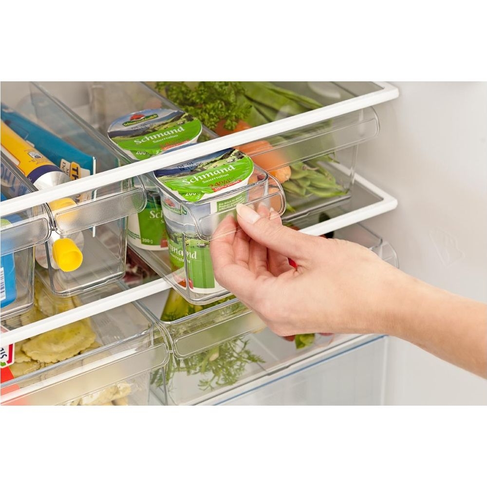 Una mano prende una coppetta di yogurt in un compartimento del frigo.
