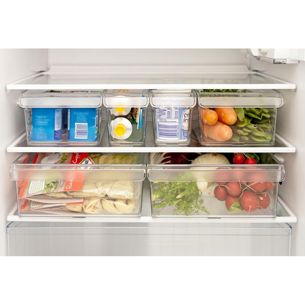 Contenitori trasparenti in plastica con cibi sugli scaffali del frigorifero. Include yogurt, uova, carote, fagiolini, pasta e ravanelli.