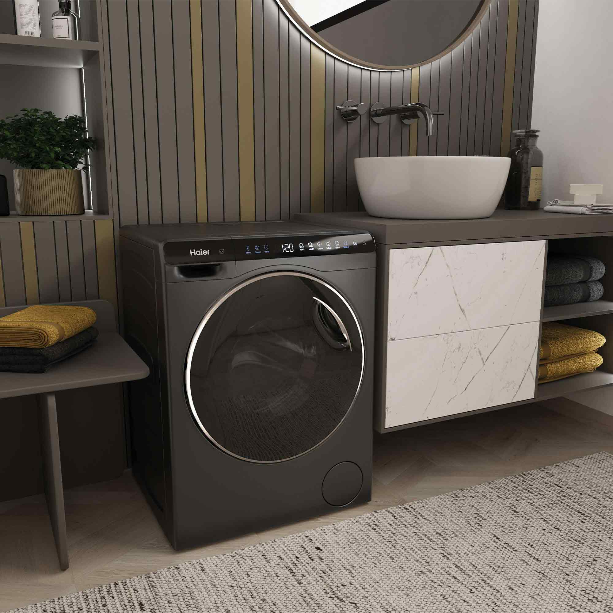 Eine dunkelgraue Haier-Waschmaschine steht in einem modernen Badezimmer mit Aufsatzwaschbecken.