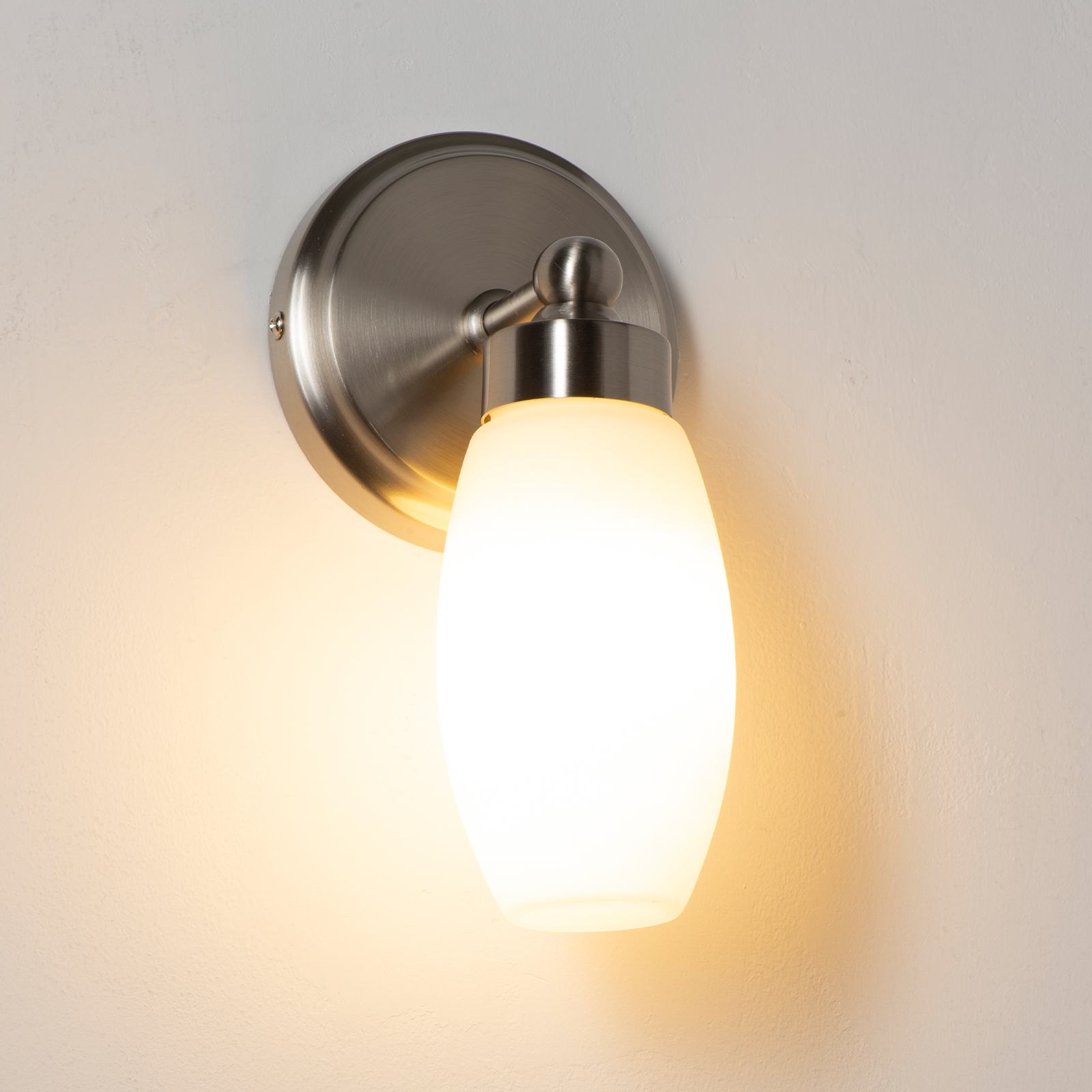 Una lámpara de pared moderna con bombilla de vidrio esmerilado y brazo de metal plateado.