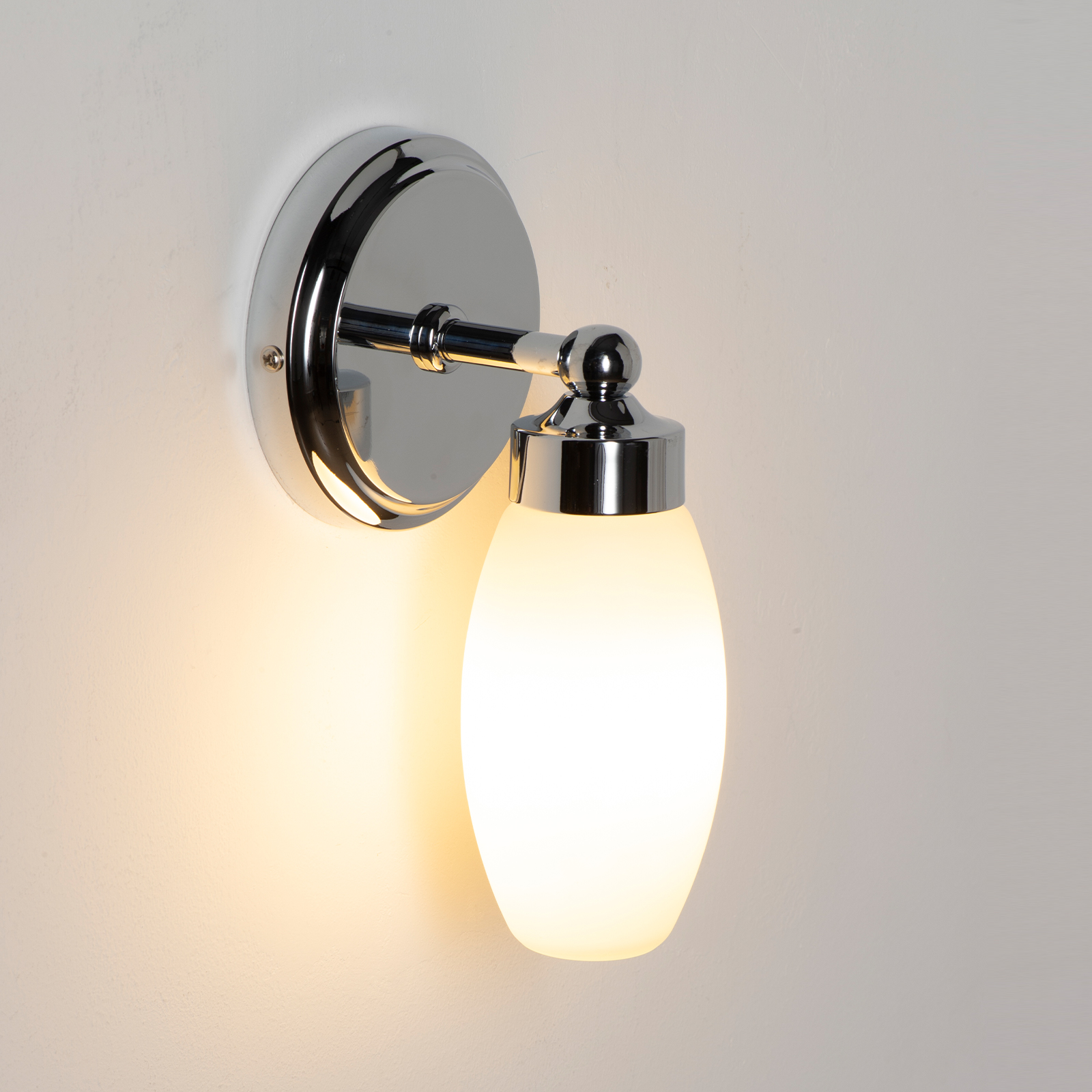 Una lámpara de pared brillante con pantalla ovalada blanca y detalles cromados.