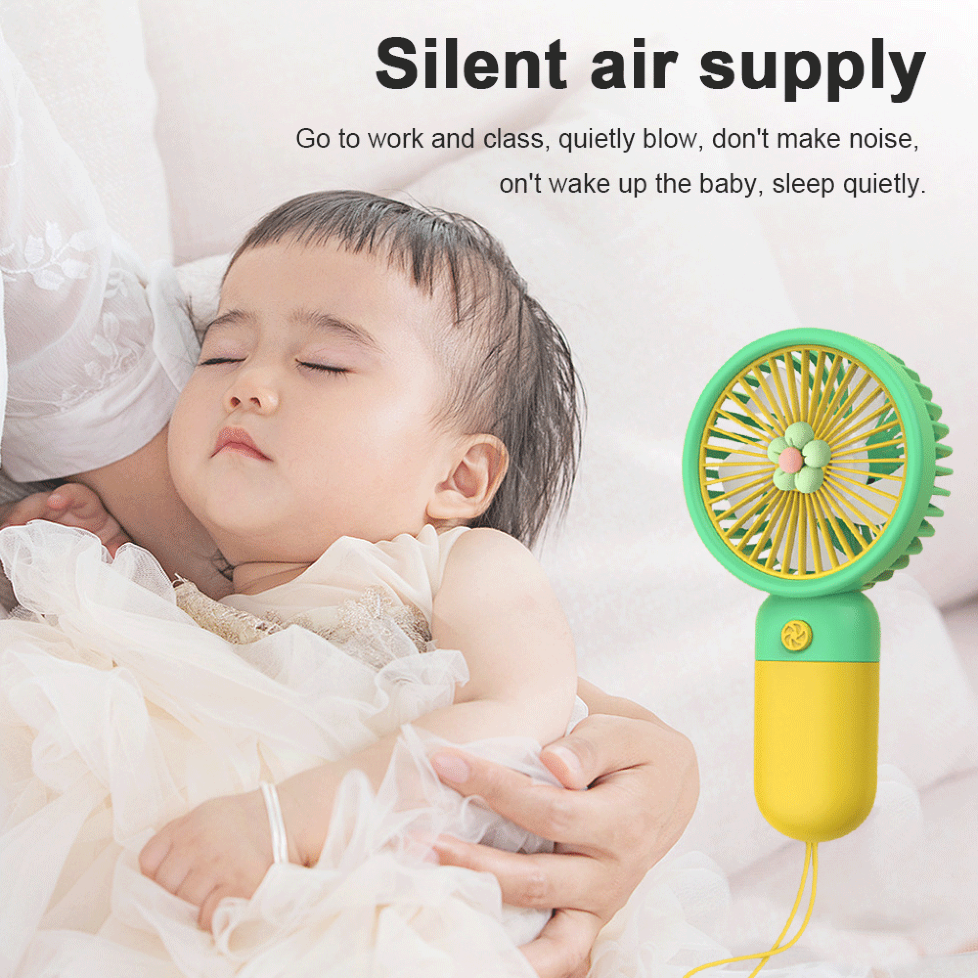 Ein Baby schläft, gehalten von einer Hand, neben einem kleinen Ventilator.