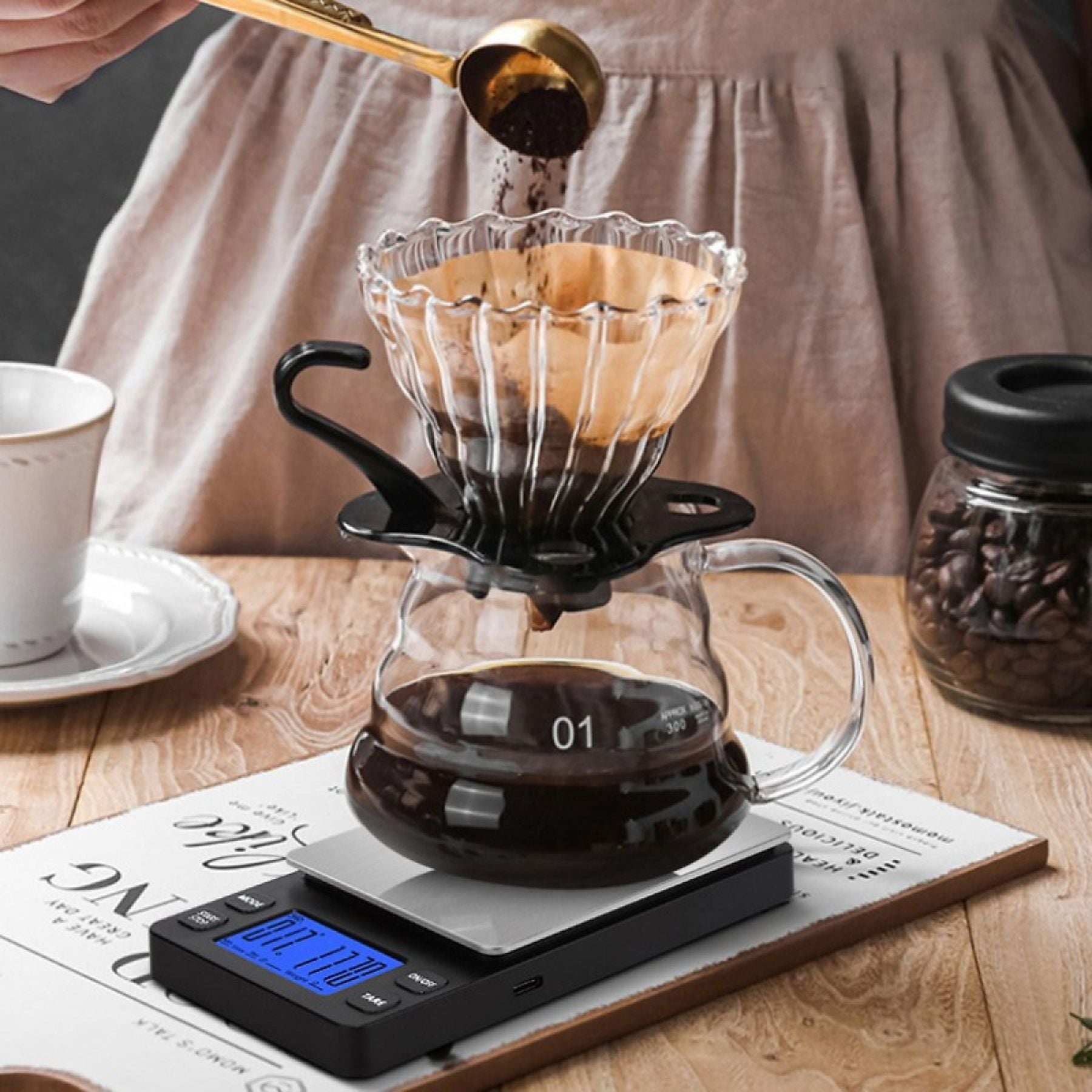 Kaffeepulver in einen Filter über einer Glaskaraffe auf einer Digitalwaage schütten.