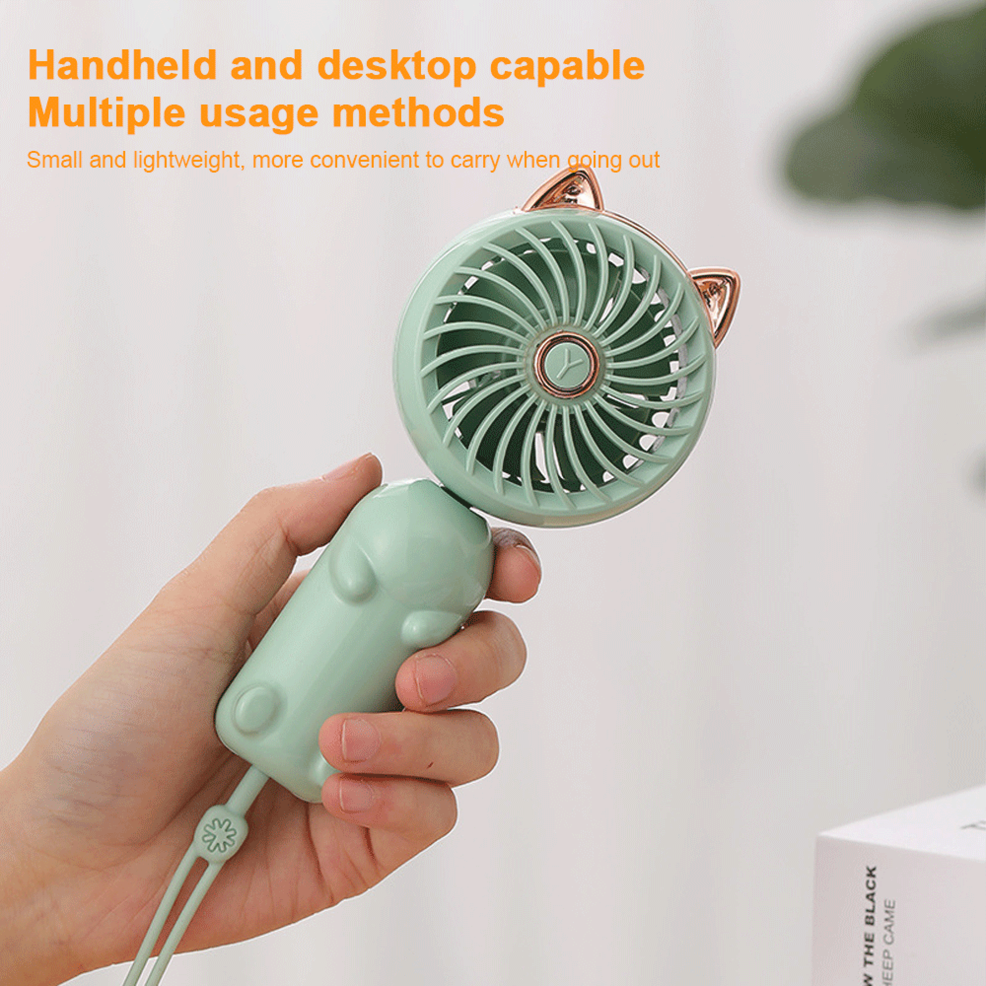 Eine Hand hält einen kleinen, hellgrünen, katzenohrigen tragbaren Ventilator.