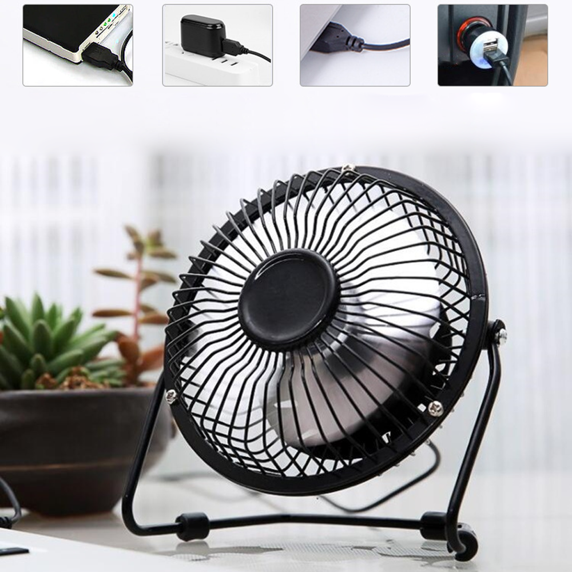 Ein kleiner schwarzer USB-Ventilator steht auf einem Tisch mit Pflanzen im Hintergrund.