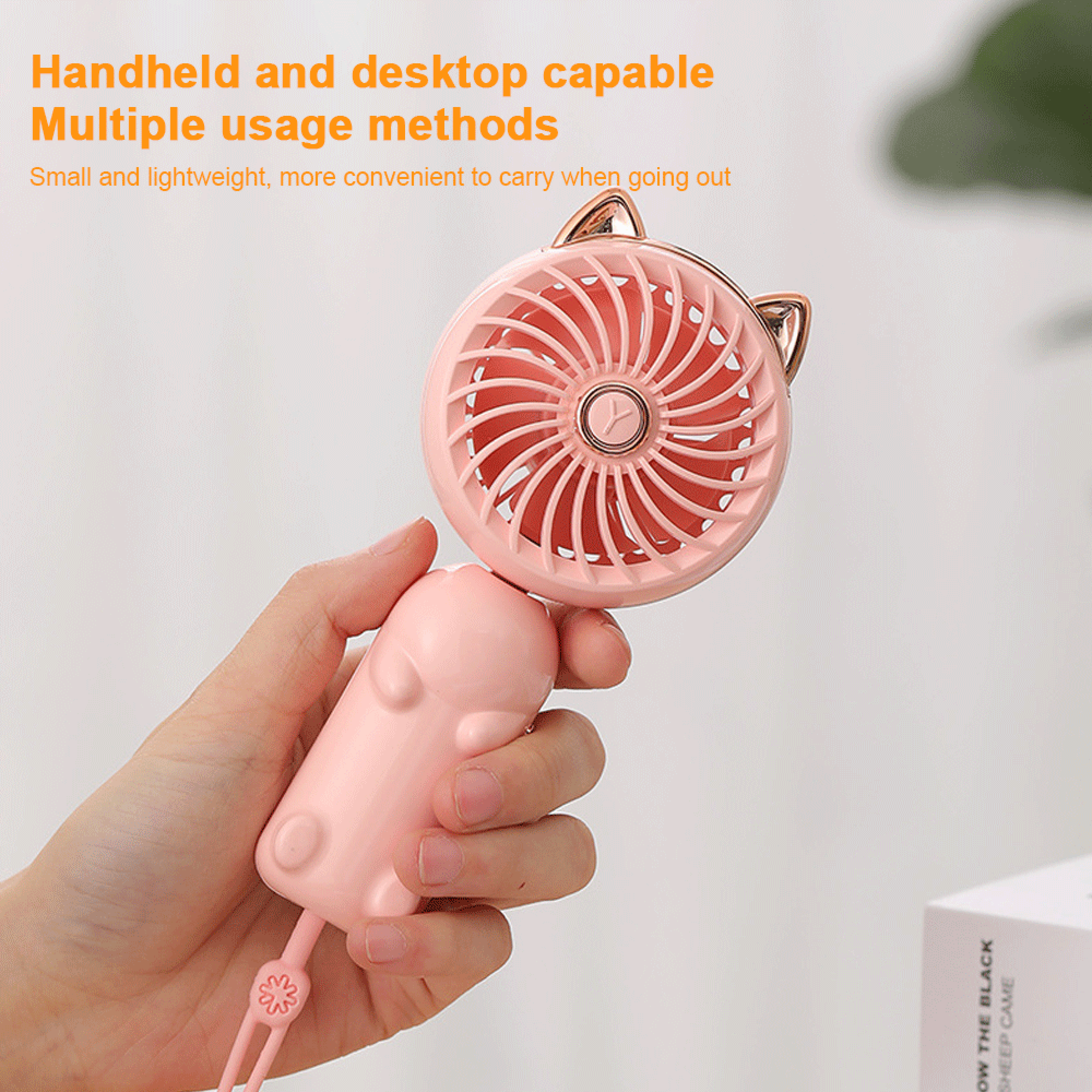 Eine Hand hält einen rosa Ventilator mit Katzenohren. Klein und tragbar.