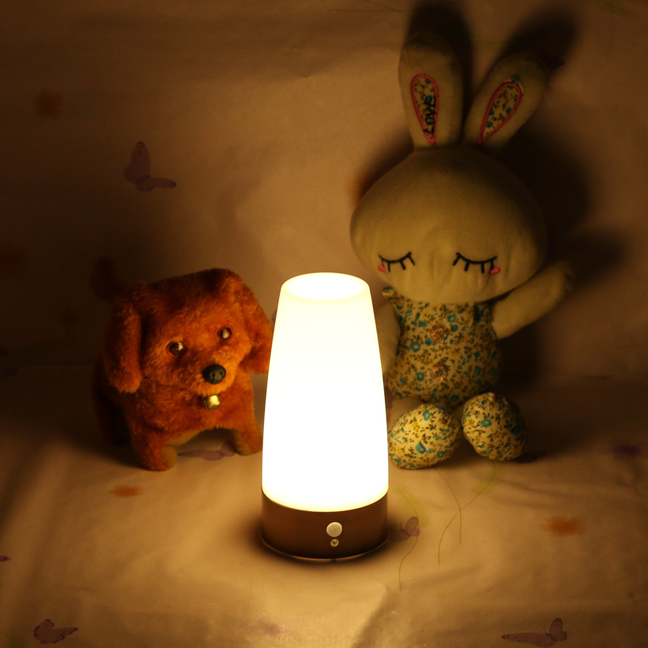Ein leuchtender Nachttisch, ein Hundespielzeug und ein Stoffhase mit Schmetterlingsmuster.