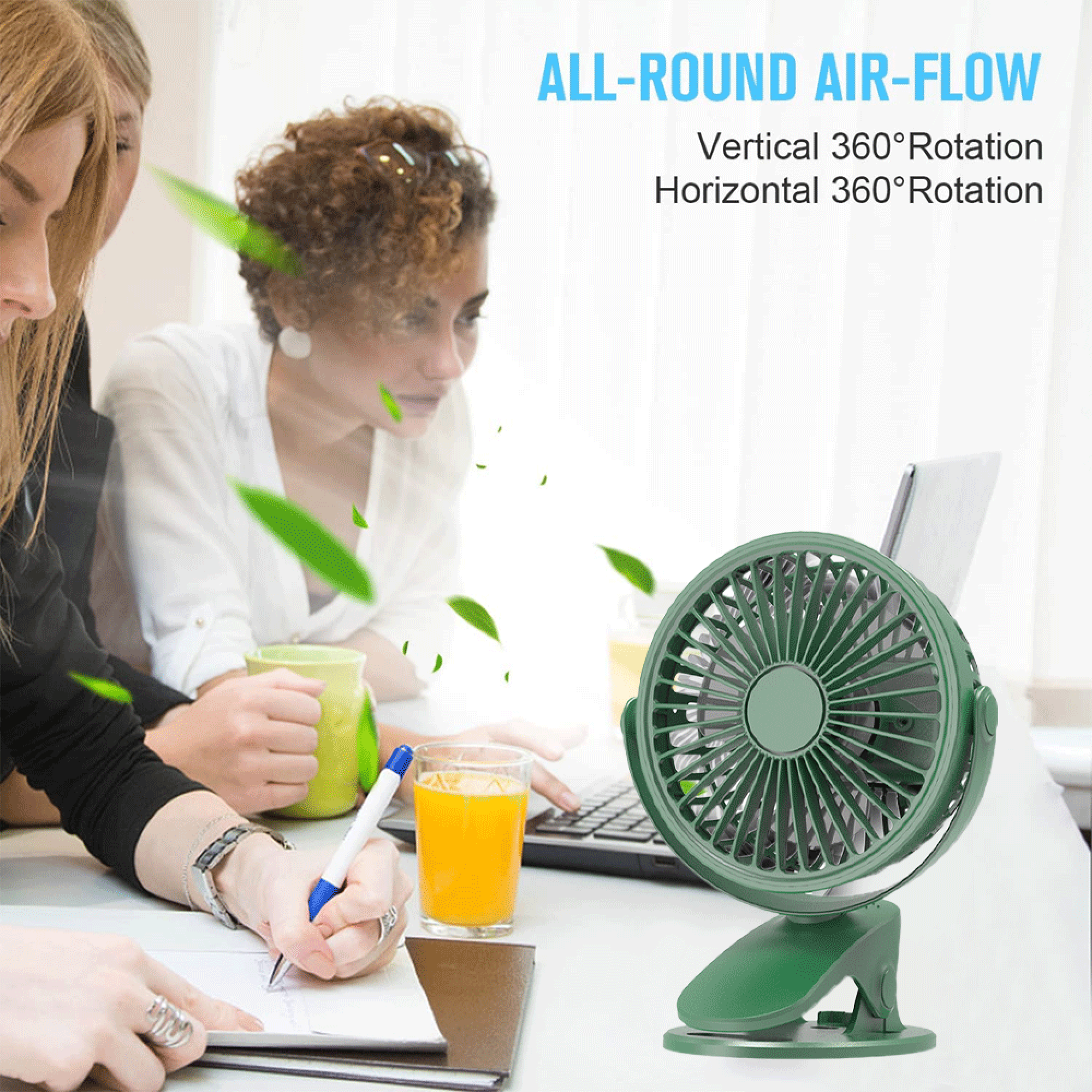 Ein grüner Ventilator steht auf einem Schreibtisch neben einem Glas Orangensaft und einer Person, die schreibt.