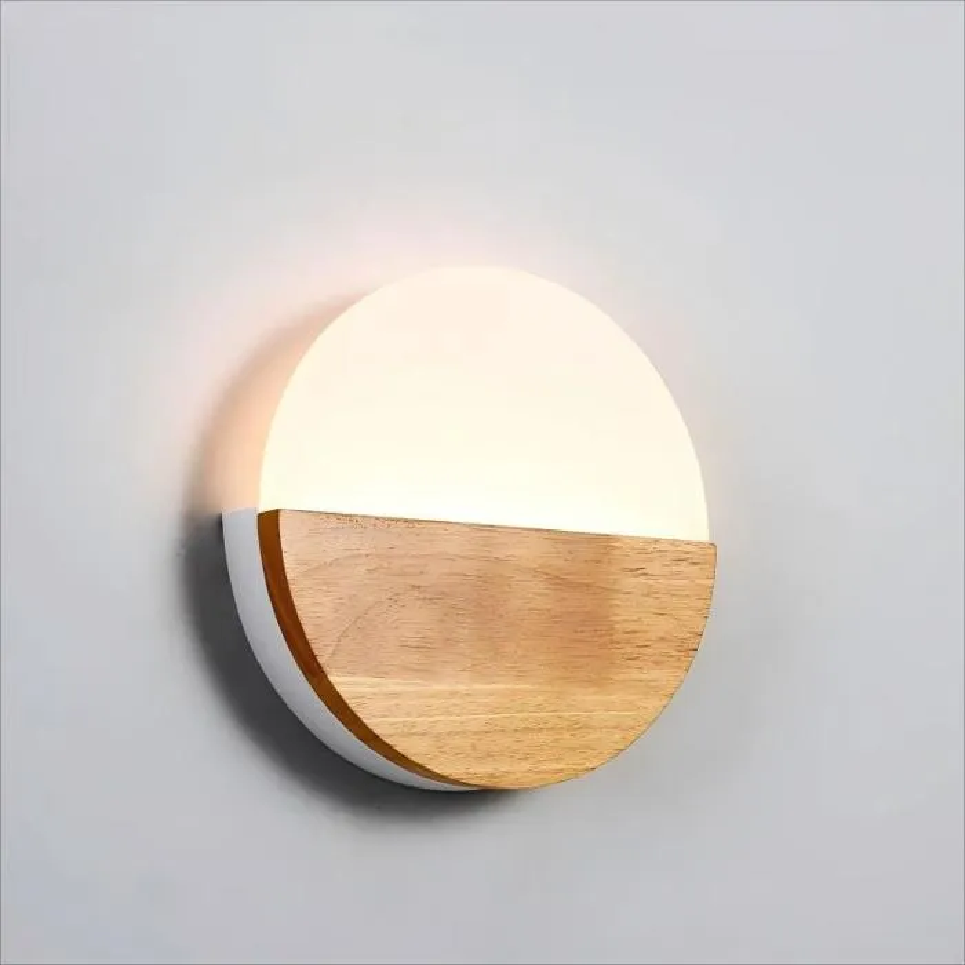 Eine runde Wandleuchte mit Holz- und weißem Gehäuse, das Licht spendet.