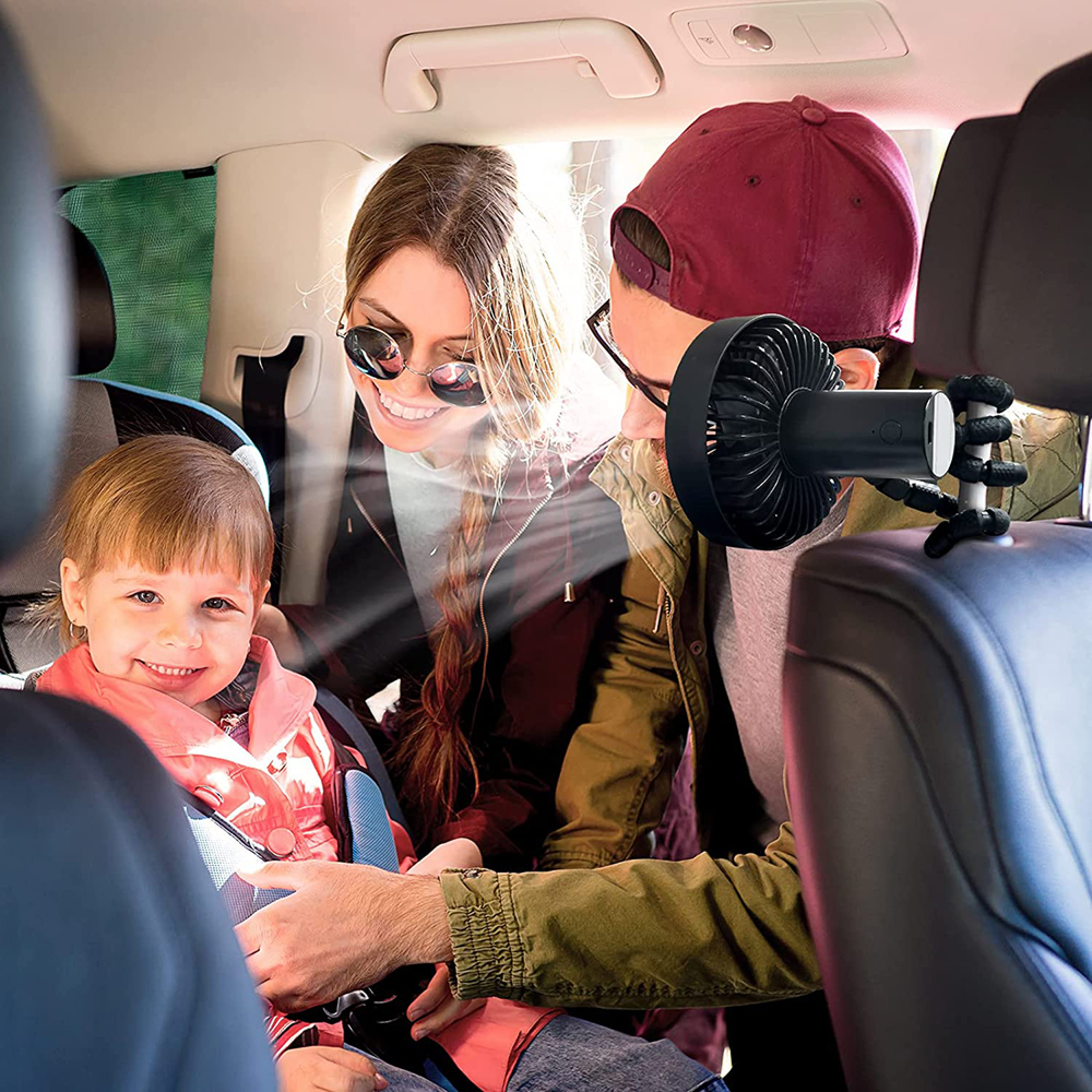 Familie im Auto mit einem Baby, das in einem Autositz sitzt. Ein Lüfter ist befestigt.