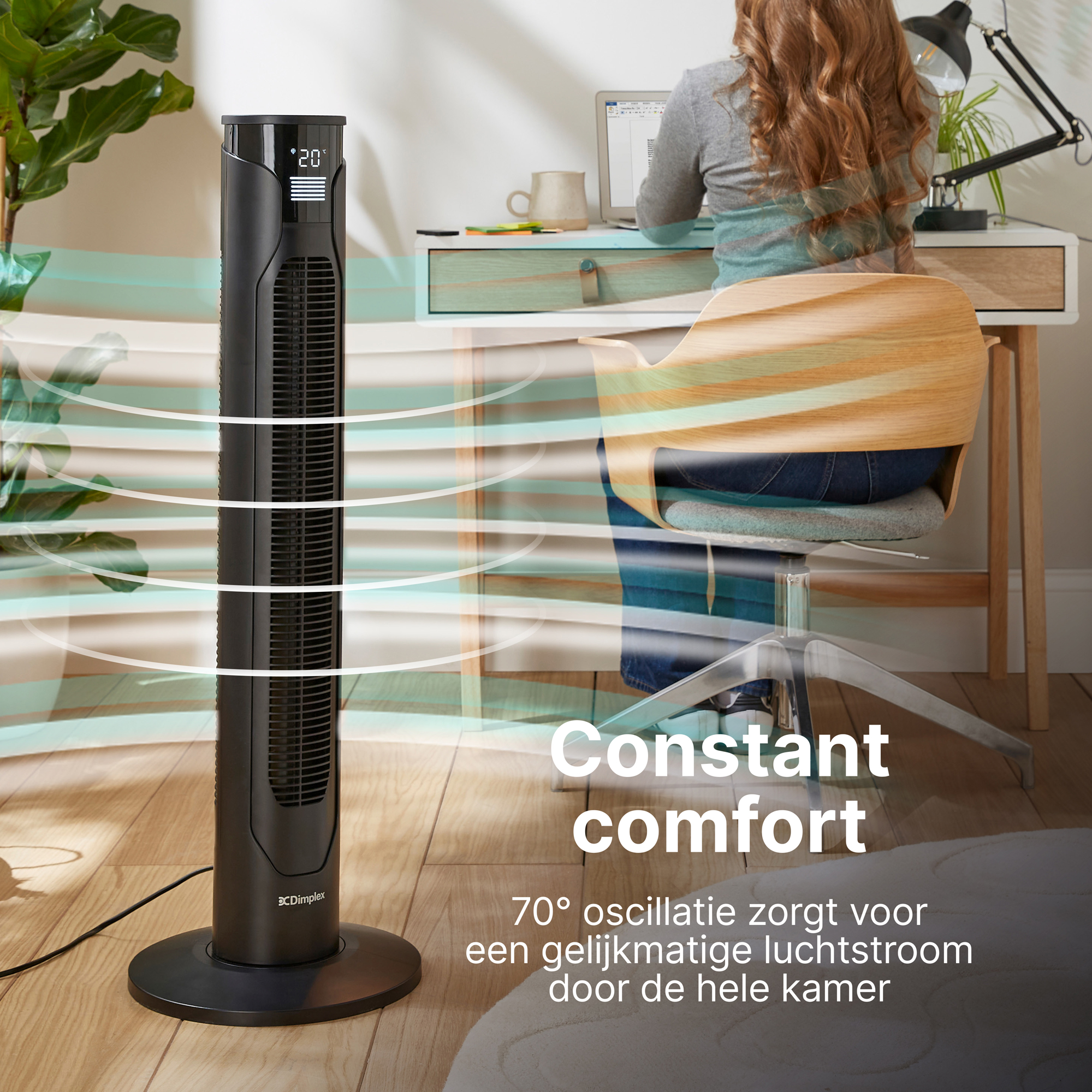 Een zwarte torenventilator staat naast een bureau waar een vrouw zit.