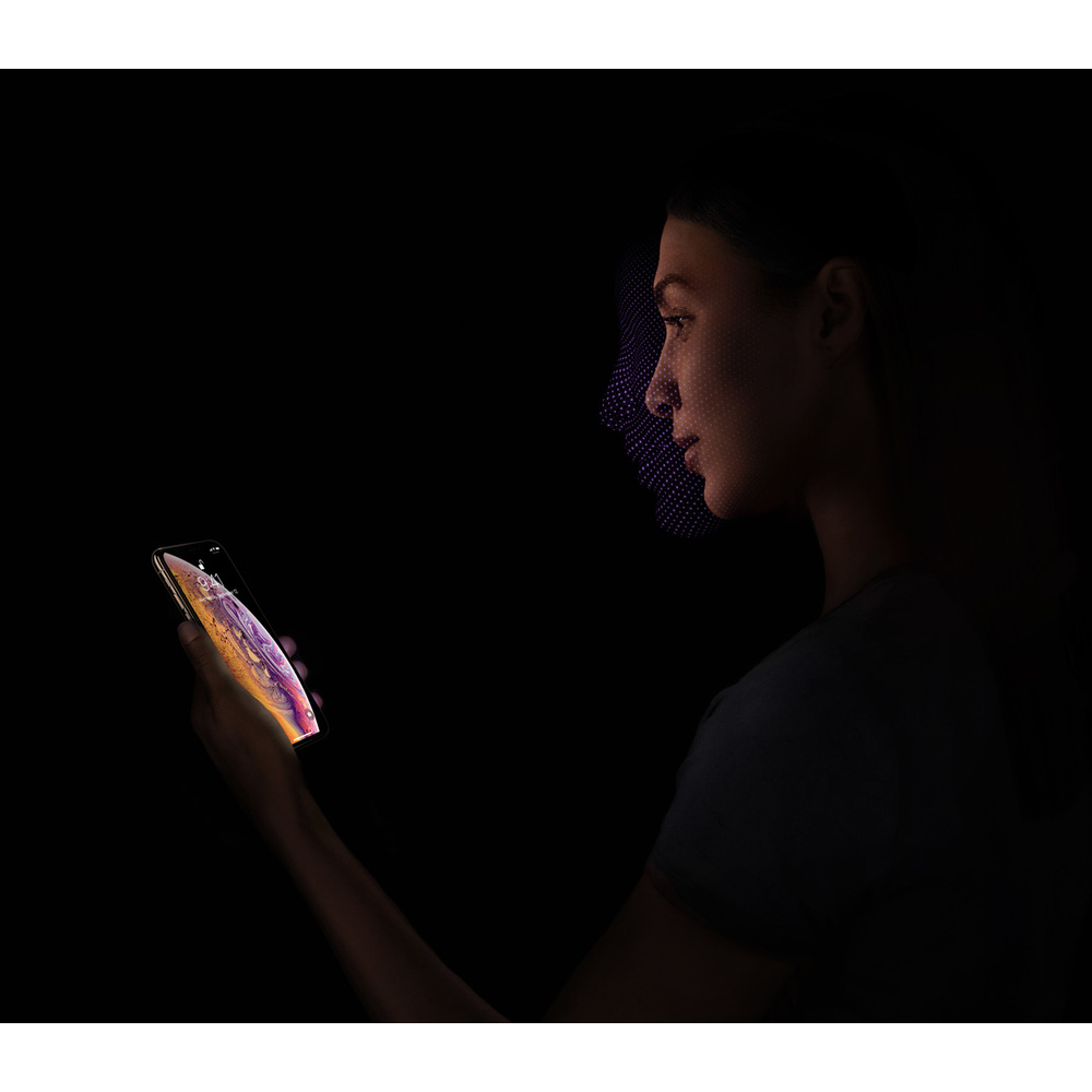 Kobieta trzyma smartfon, jej twarz jest skanowana przez fioletowy wzór punktowy.
