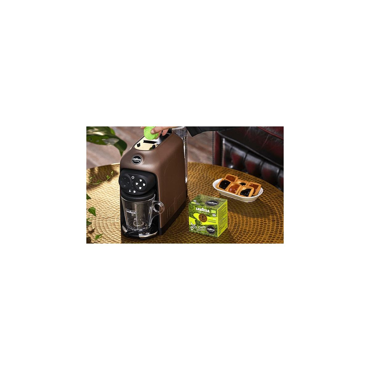 Una cafetera Lavazza marrón con taza de cristal y caja de Lavazza Eco Caps.