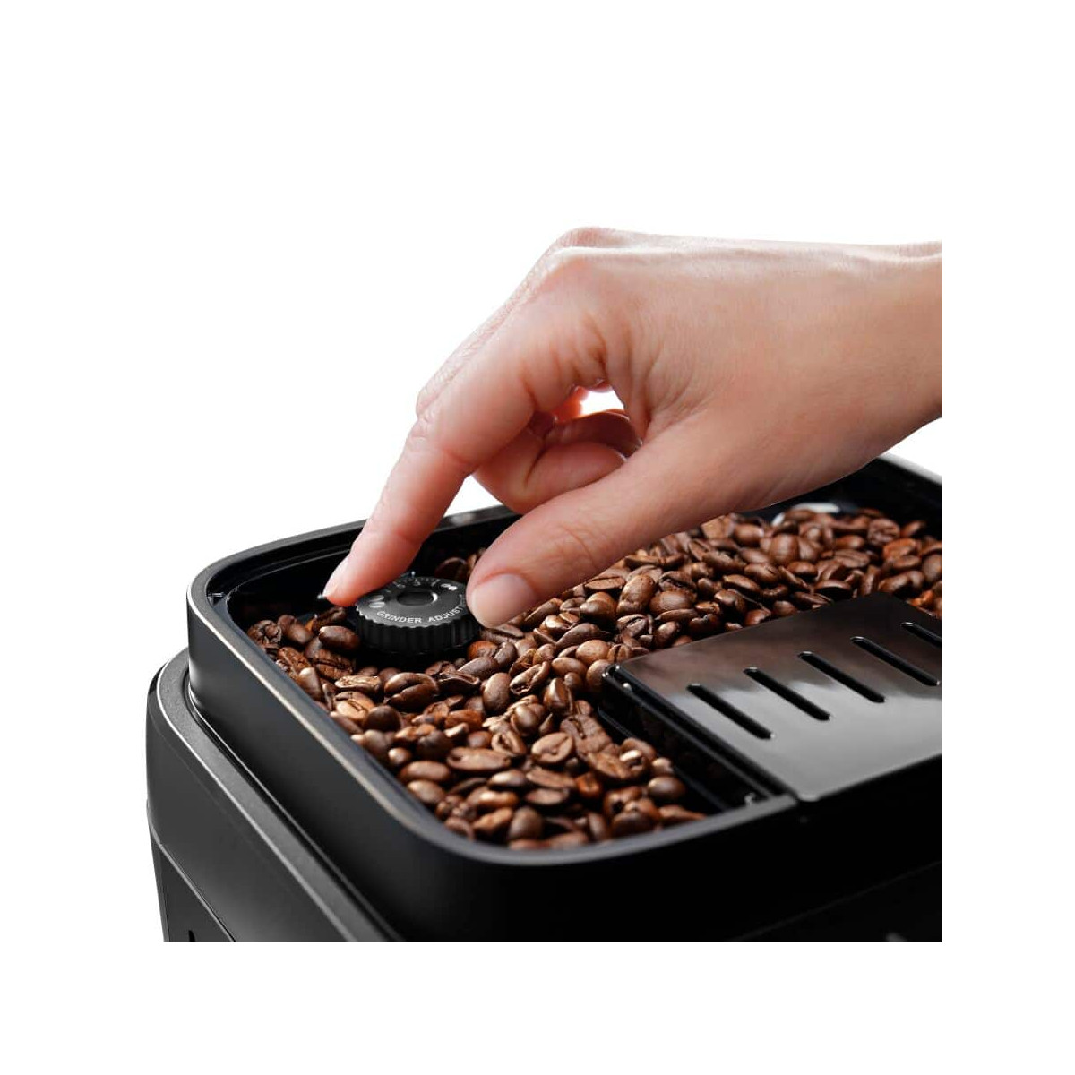 Eine Hand verstellt einen Knopf in einem Behälter voller Kaffeebohnen.