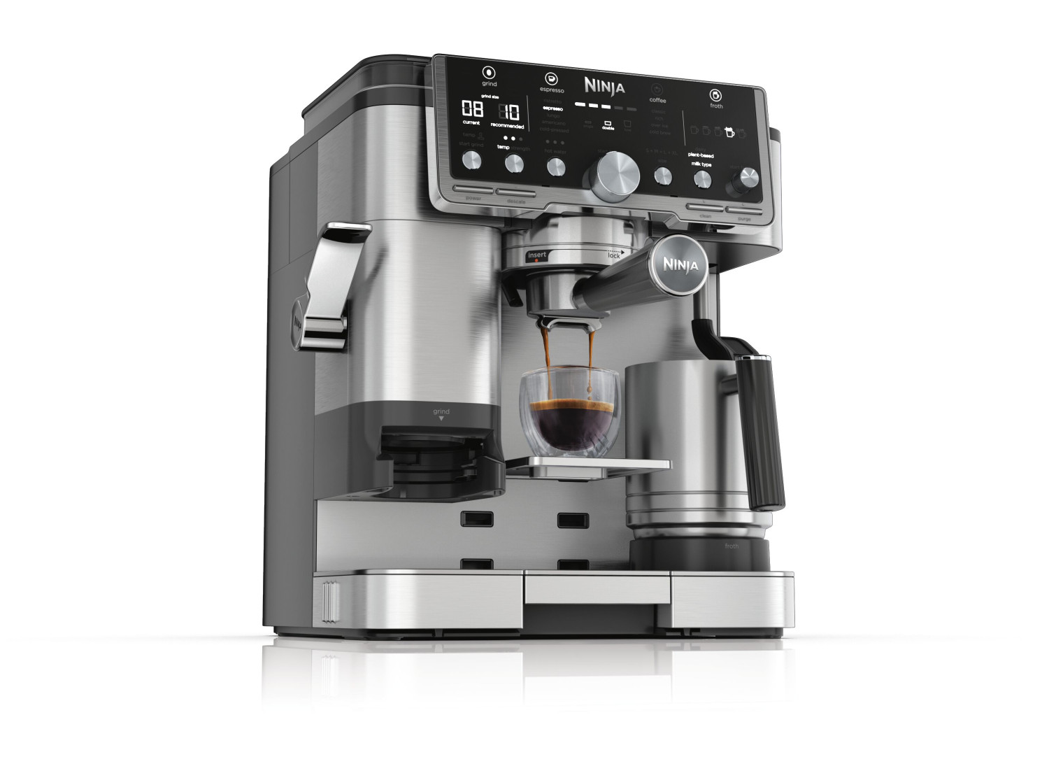 Een zilveren koffiezetapparaat zet espresso in een glas. Melkkan ernaast.