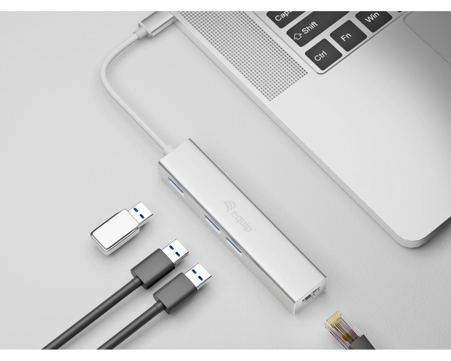 Hub USB argentato con cavi e laptop su sfondo grigio.