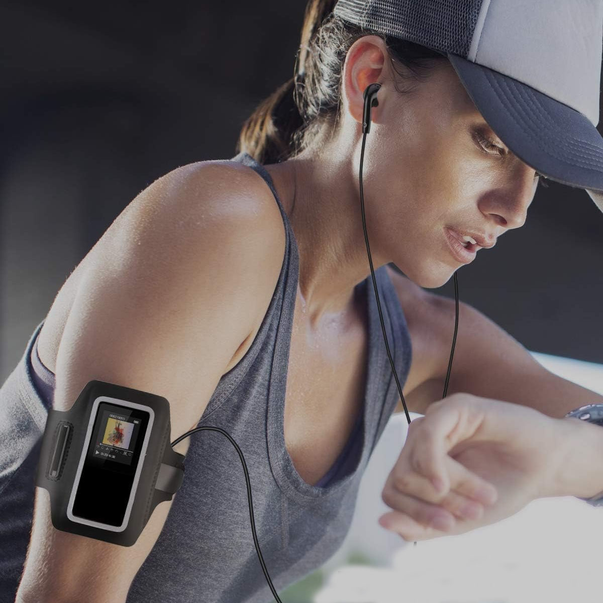Eine Frau mit Kopfhörern und Armband-Handy hält ihr Handgelenk. Trainiert.