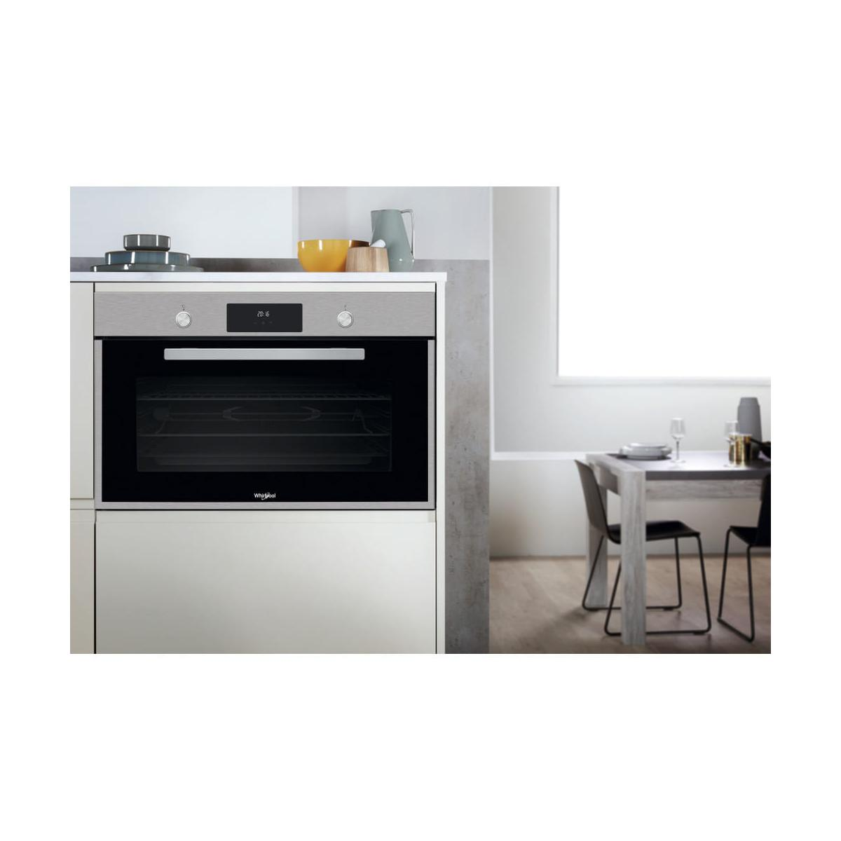 Un horno empotrado moderno en una cocina, junto a una mesa de comedor con sillas.