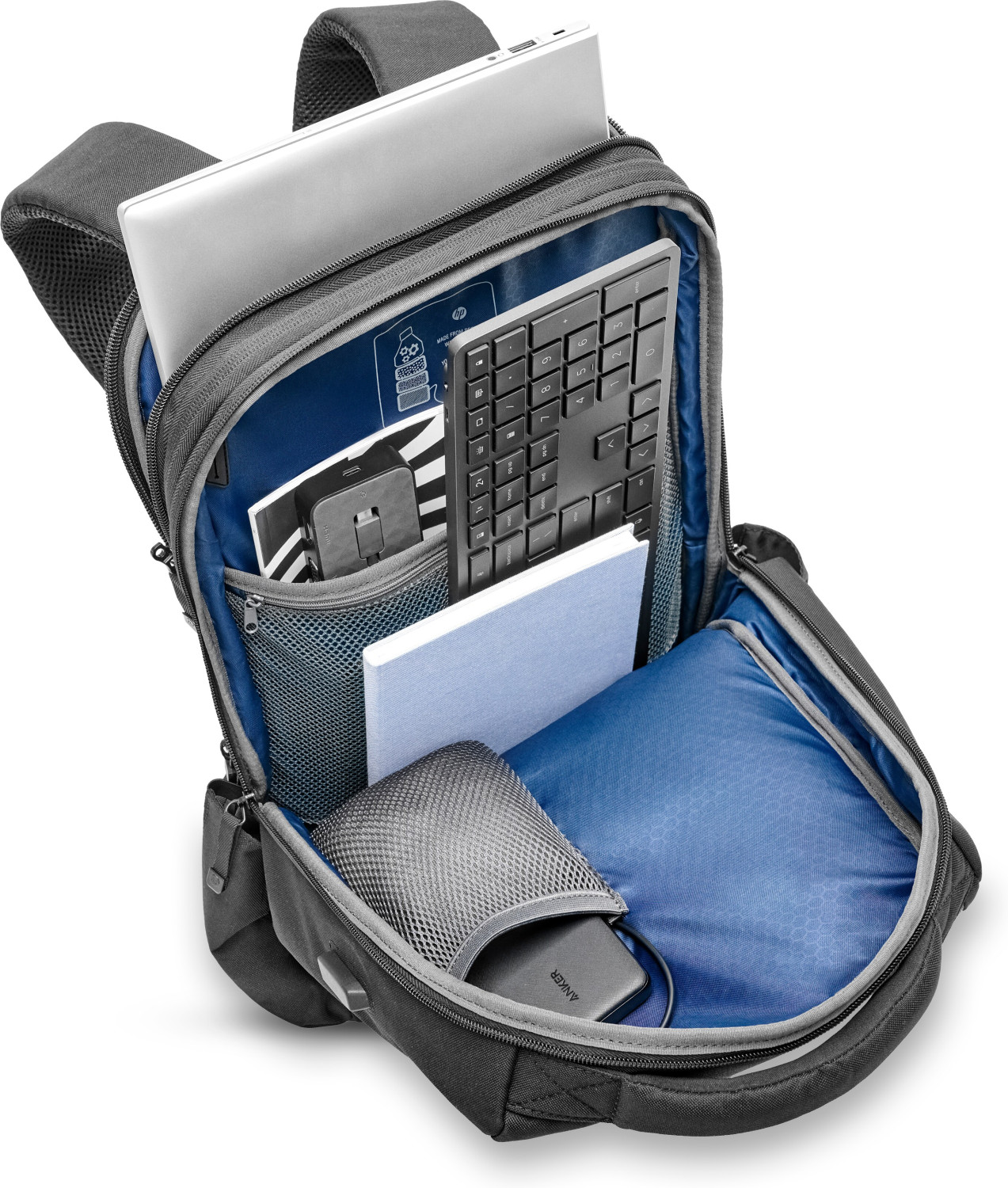 Zaino grigio aperto con laptop, tastiera, taccuino e power bank all'interno.
