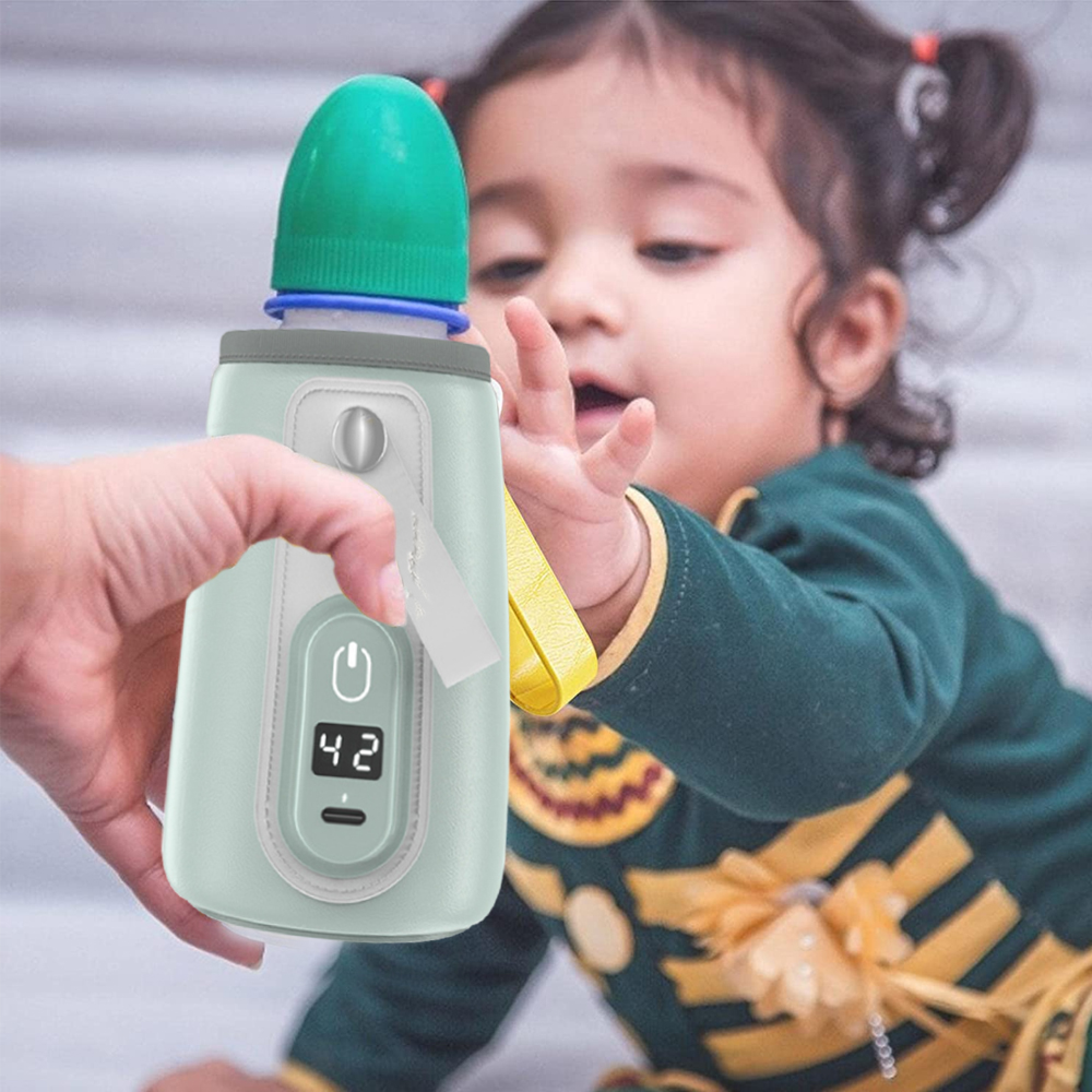 Eine Hand hält einen Babyflaschenwärmer mit Digitalanzeige und reicht einem Baby.
