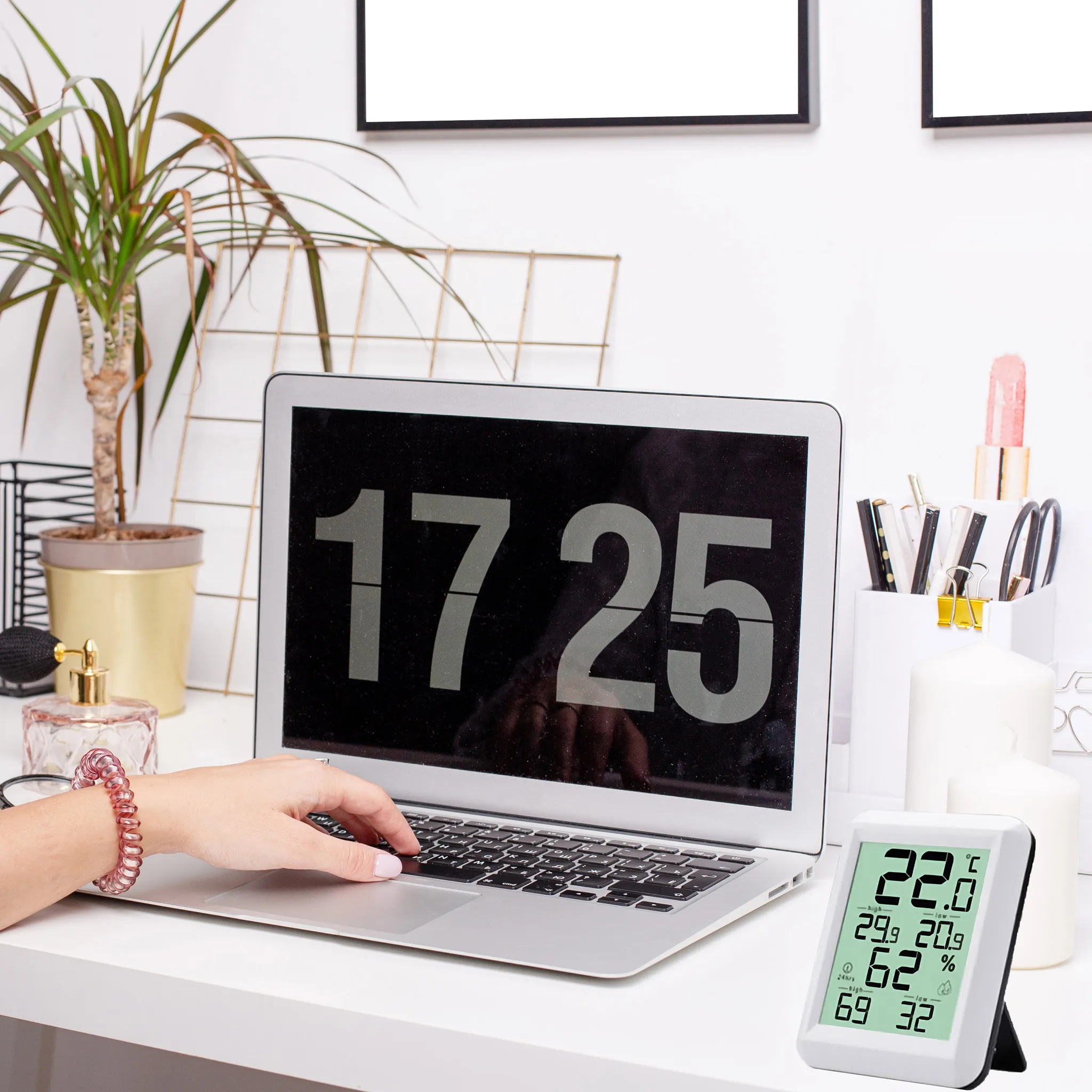 Laptop auf Schreibtisch zeigt 17:25. Hand tippt. Digitales Thermometer zeigt Temp, Feuchte.