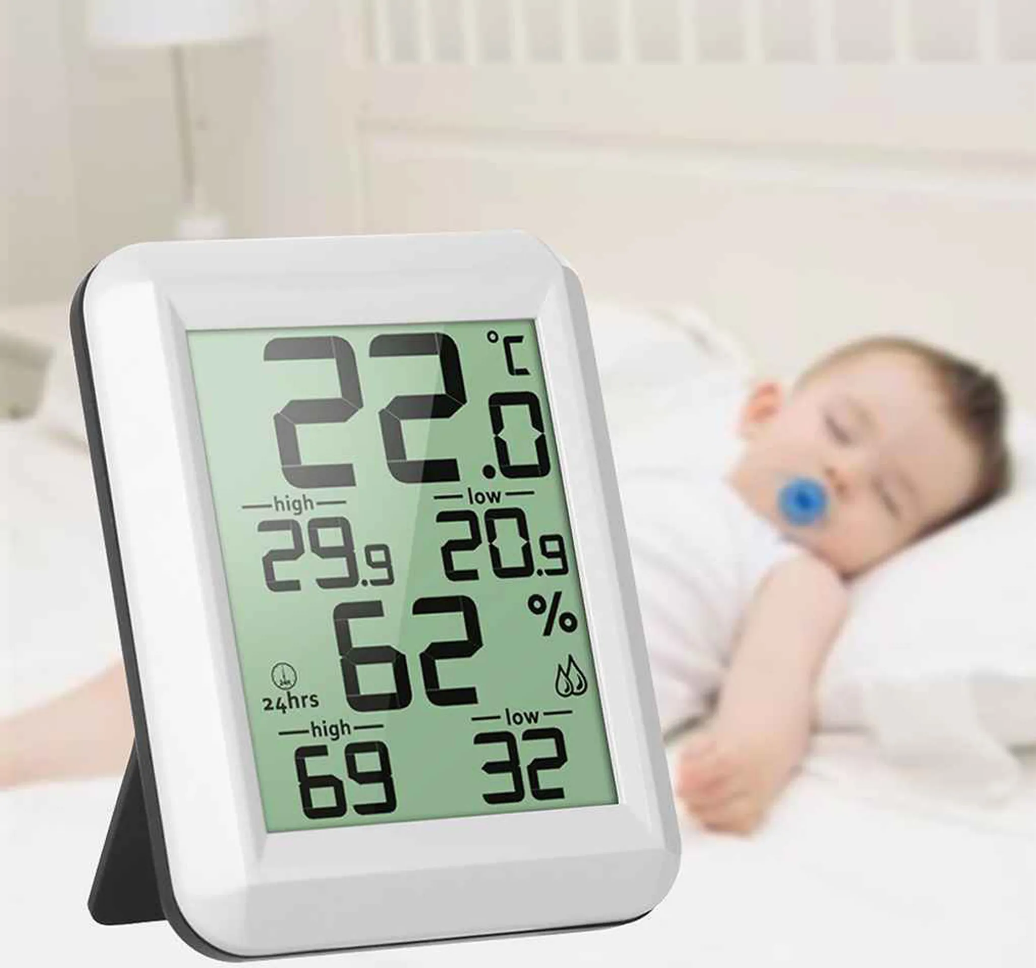 Ein Digitalthermometer zeigt 22°C an, daneben schläft ein Baby mit Schnuller.