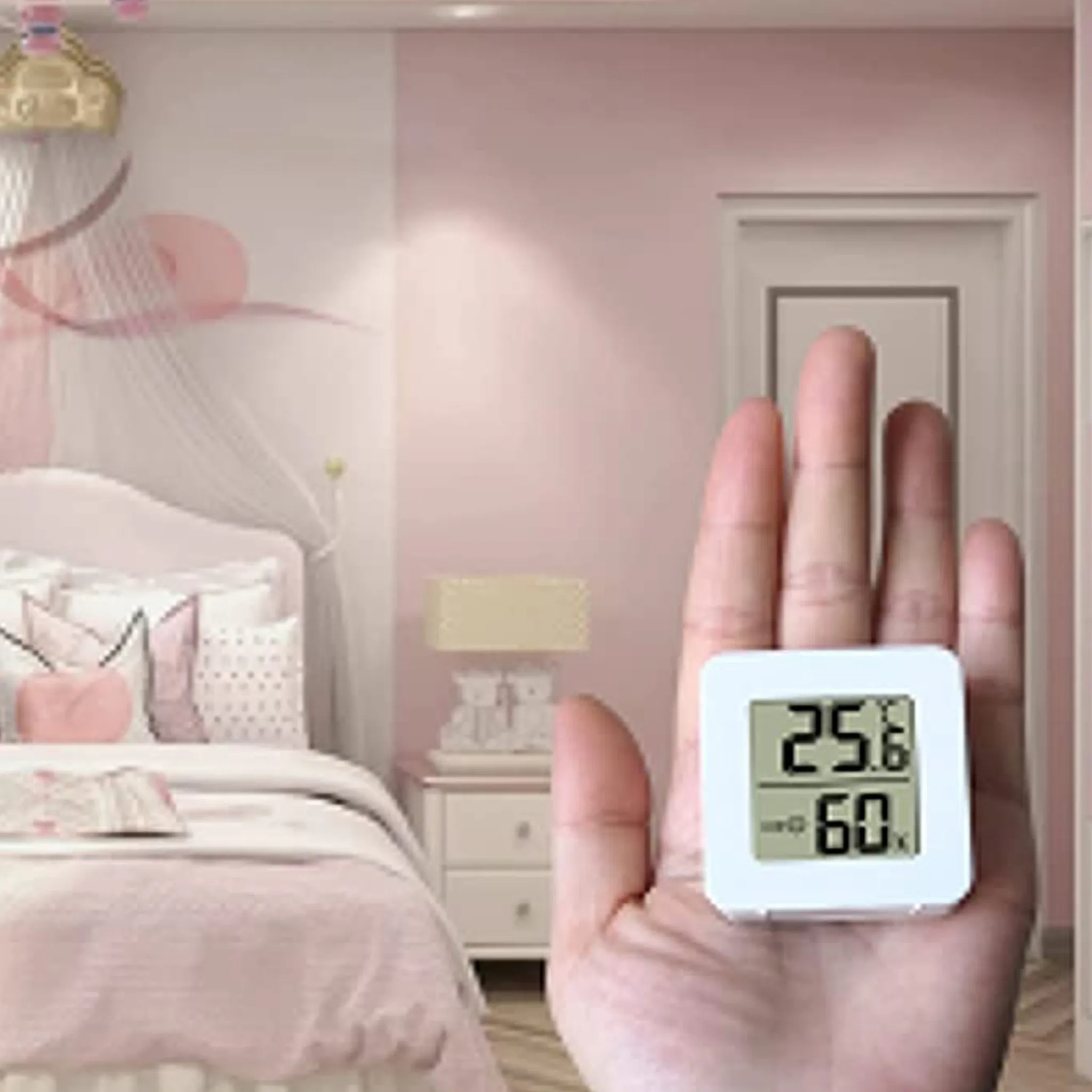 Eine Hand hält ein kleines weißes Thermometer mit 25,6 Grad und 60 % Luftfeuchtigkeit.