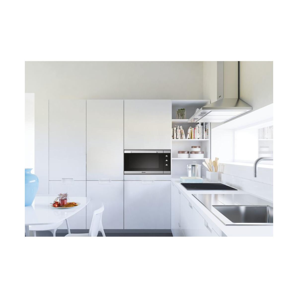 Moderna cucina bianca con microonde, piano cottura, lavello e tavolo da pranzo.