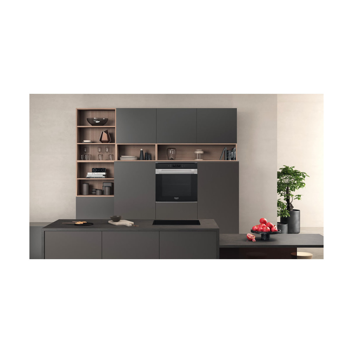 Cucina moderna con mobili scuri, forno, isola e ciotola di frutta.