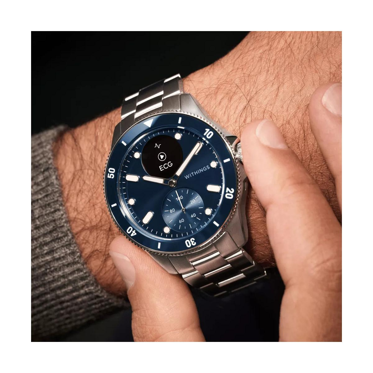 Ein Mann trägt eine silberne Smartwatch mit blauem Zifferblatt, die EKG- und Herzfrequenzdaten anzeigt.