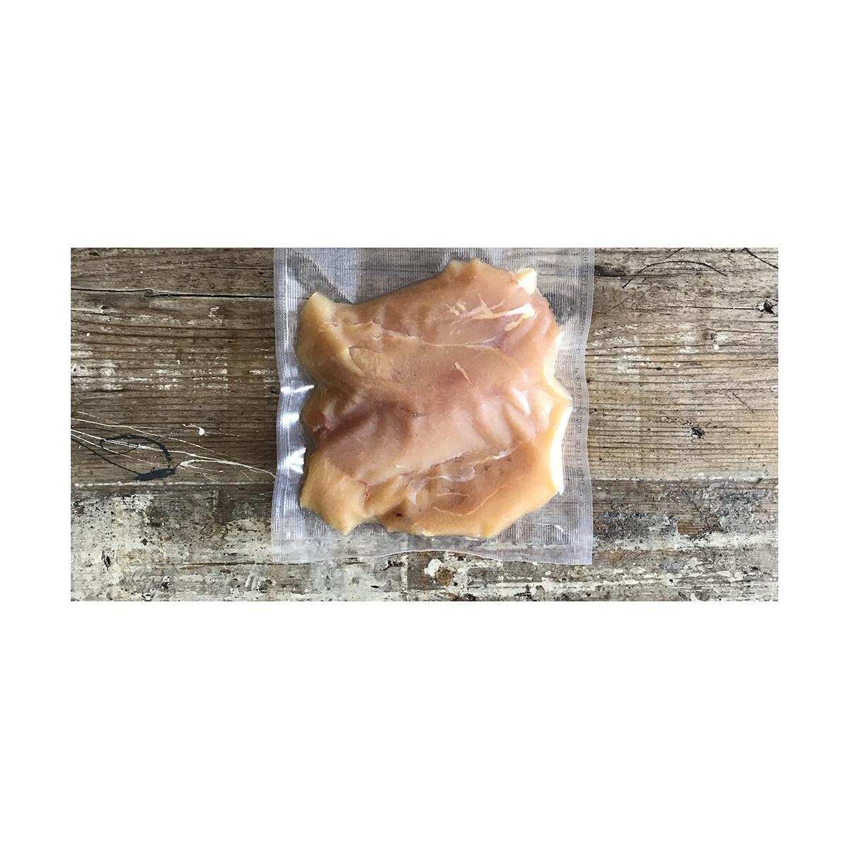 Un petto di pollo crudo sottovuoto su legno.