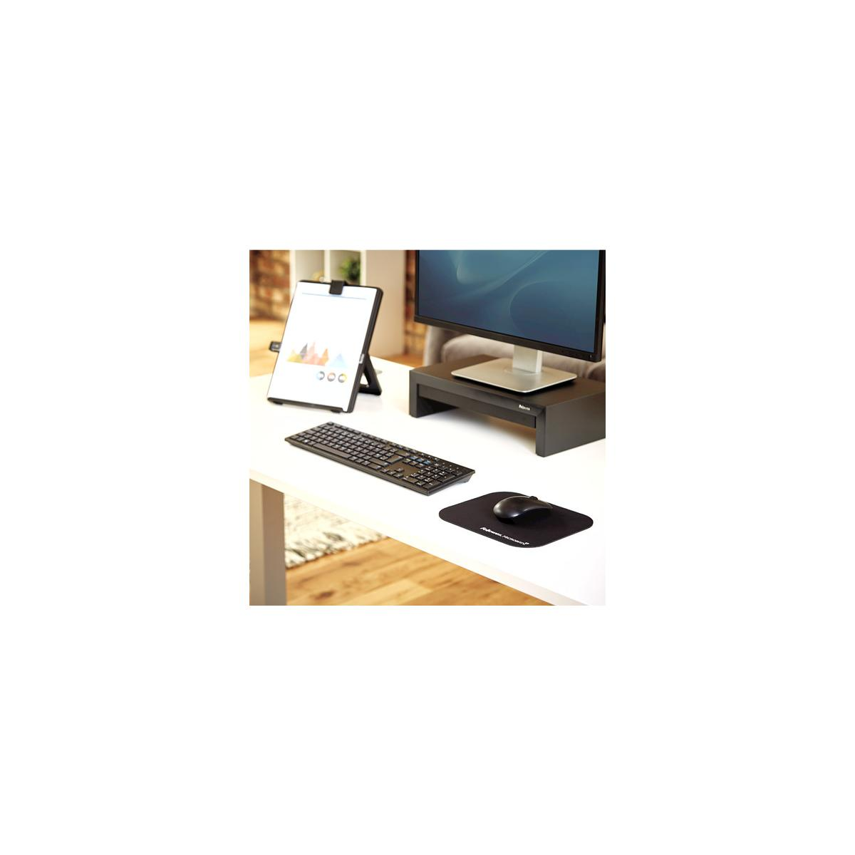 Escritorio con monitor, teclado, ratón y soporte para bloc de notas con gráficos.