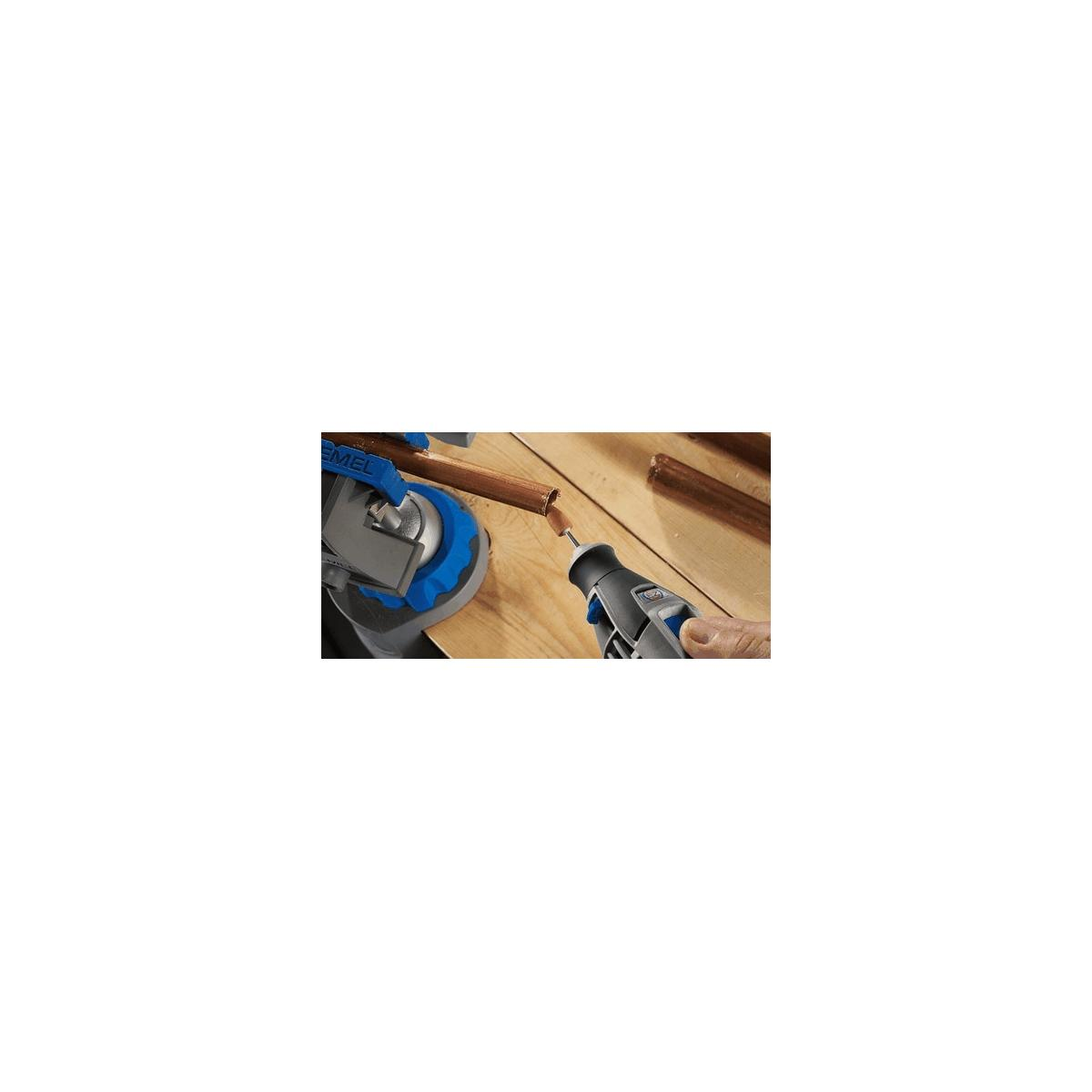 Un artesano trabaja en una tubería con una herramienta Dremel sobre una superficie de madera.