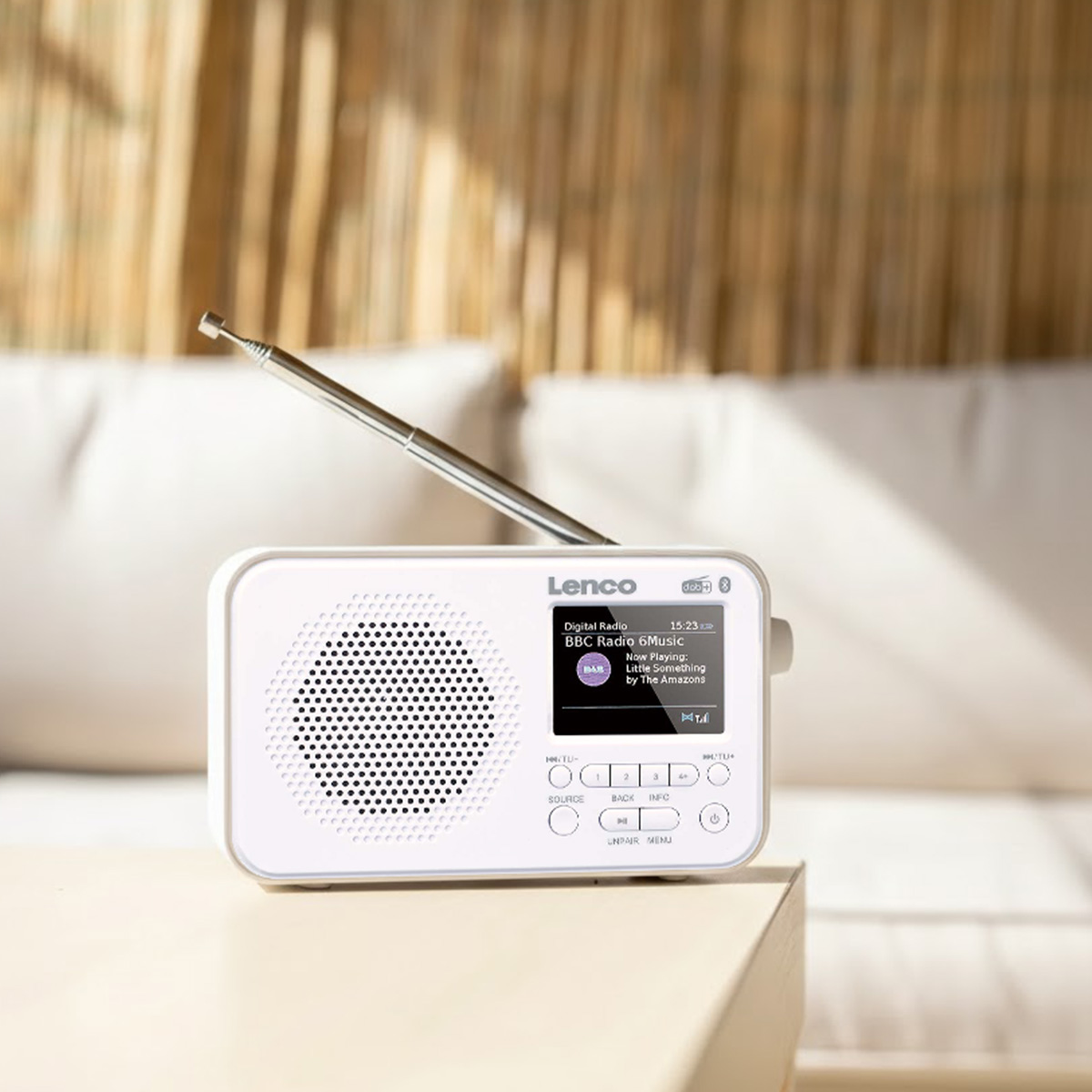 Een witte Lenco digitale radio met uitgeschoven antenne staat op tafel.