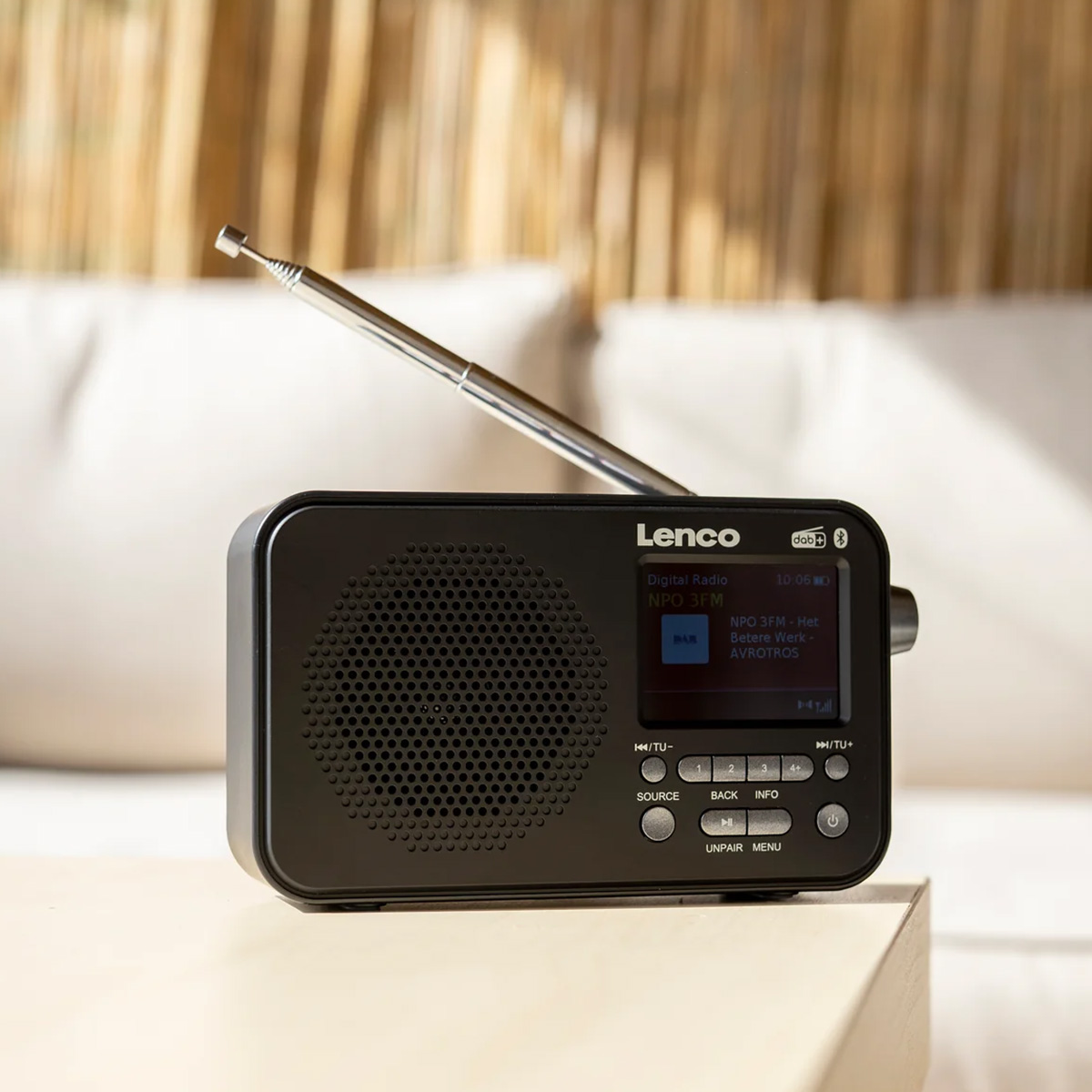 Une radio Lenco DAB+ noire avec antenne déployée est posée sur une table.