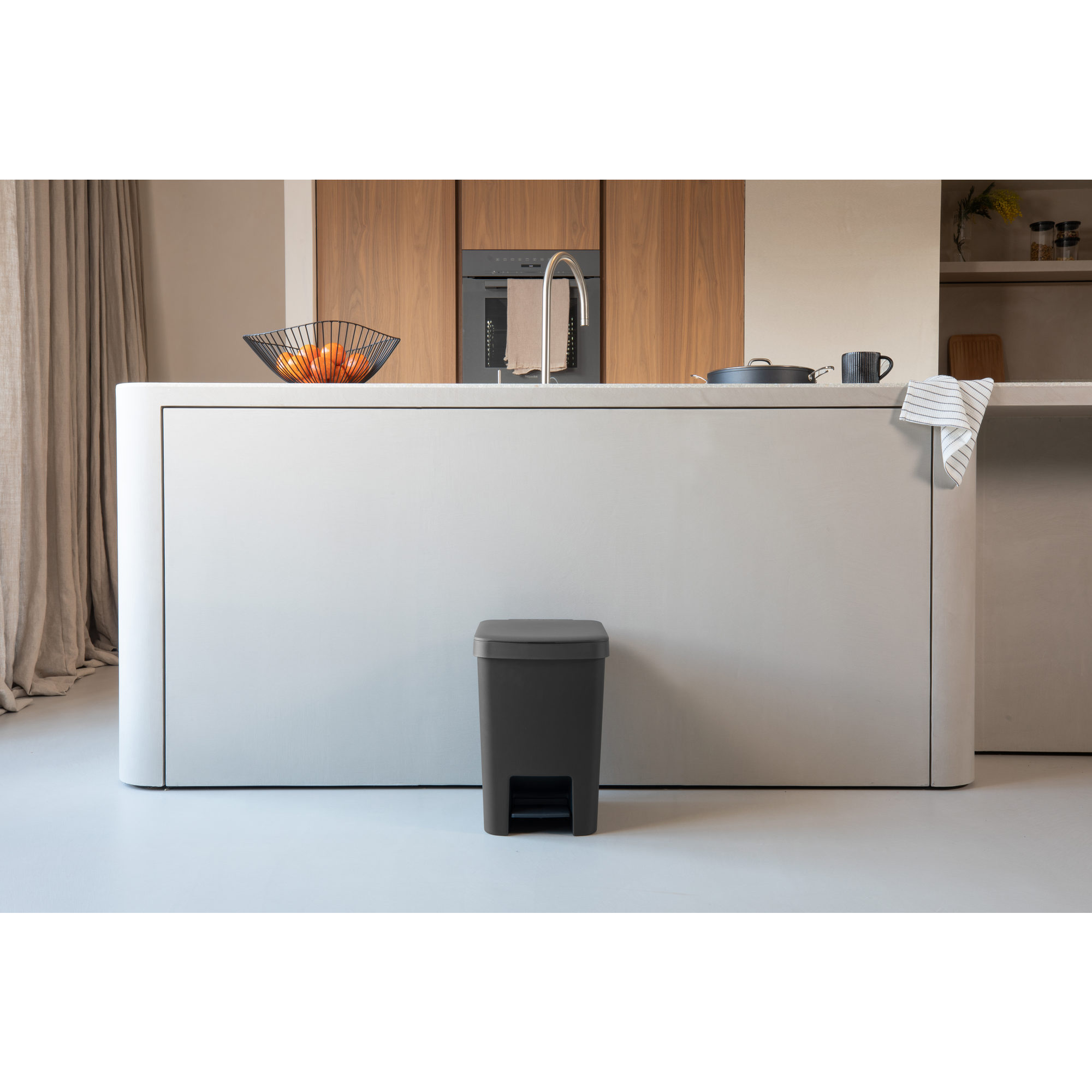 Moderne keuken met eiland, fruitschaal en prullenbak.