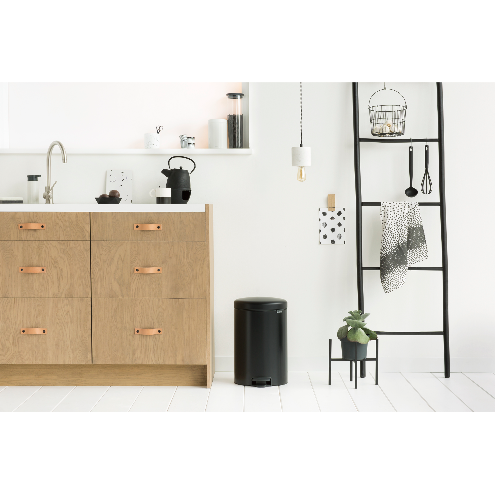 Moderne keuken met houten kasten, zwarte prullenbak en ladderrek.