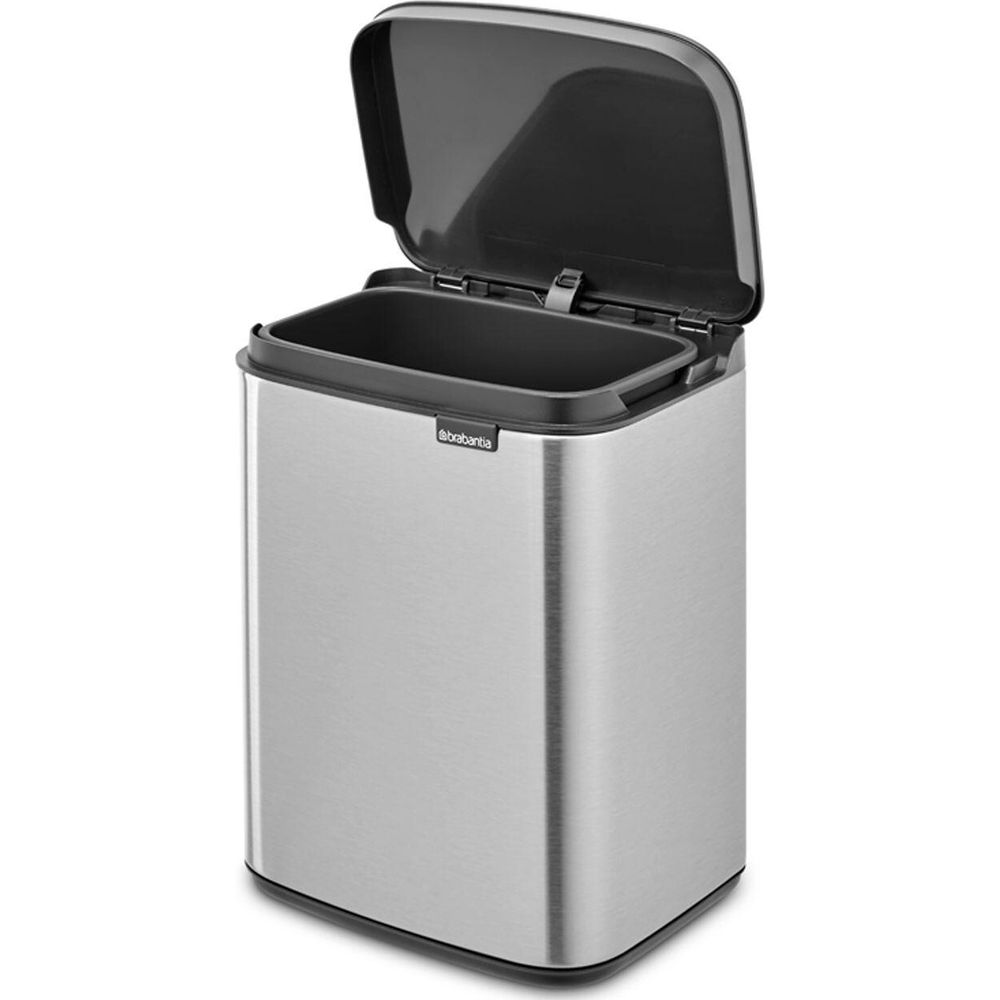 Een zilveren Brabantia prullenbak met het deksel open, die het donkere interieur onthult.